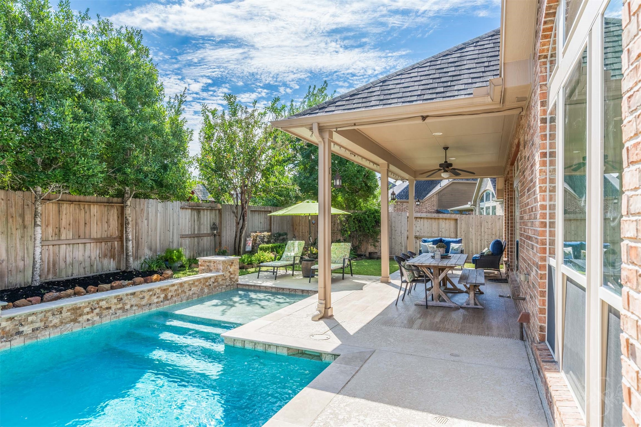 The covered patio offers an inviting setting for outdoor dining and relaxed conversation overlooking the sparkling pool. Beautiful landscaping and generous space for seating make this backyard retreat a wonderful place to gather with family and friends.