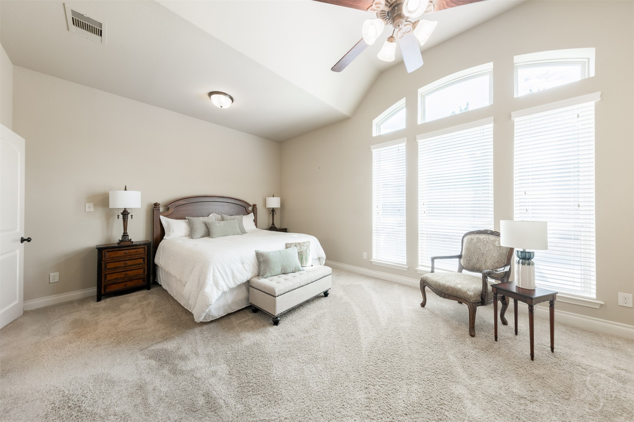 A stunning 12-foot gabled ceiling and expansive windows create an elegant retreat in the spacious primary suite. Generous proportions allow for a comfortable sitting area, perfect for quiet reading or unwinding at the end of the day.