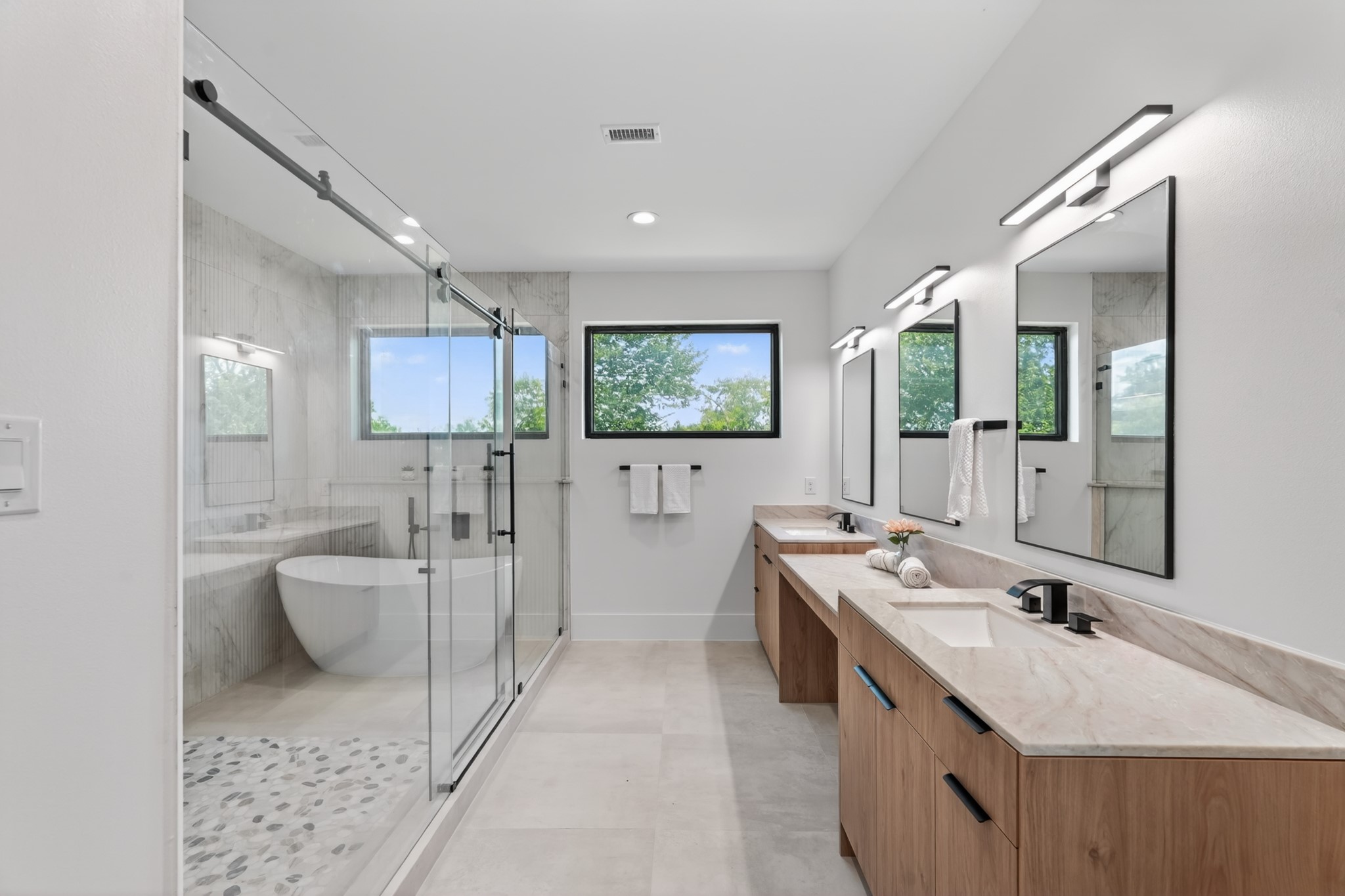 Luxurious primary bathroom featuring dual vanities, a dedicated makeup vanity, a spacious walk-in shower, a separate soaking tub, and abundant natural light.