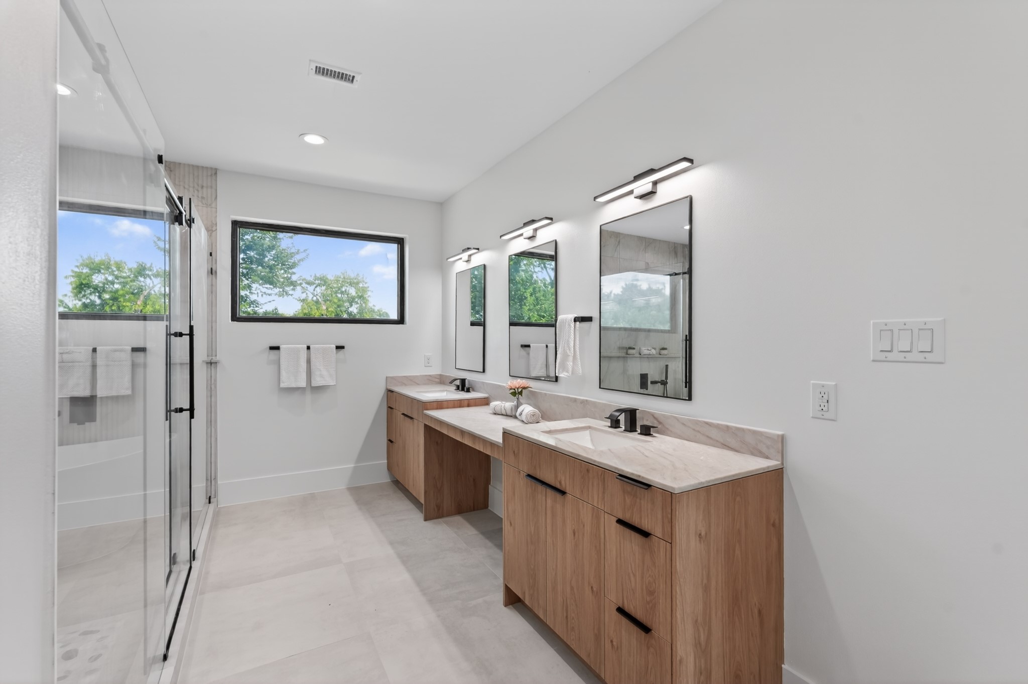 Luxurious primary bathroom featuring dual vanities, a dedicated makeup vanity, a spacious walk-in shower, a separate soaking tub, and abundant natural light.