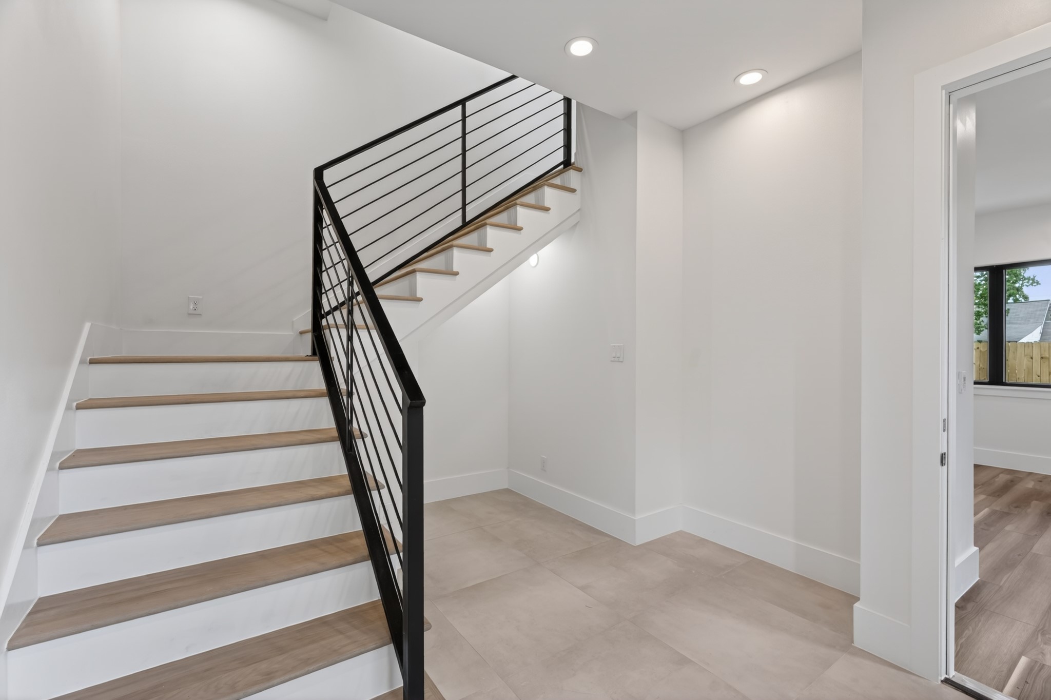 Bright and inviting foyer featuring high ceilings, abundant natural light, and an open layout. The modern staircase with sleek railing creates a striking architectural focal point and a grand first impression