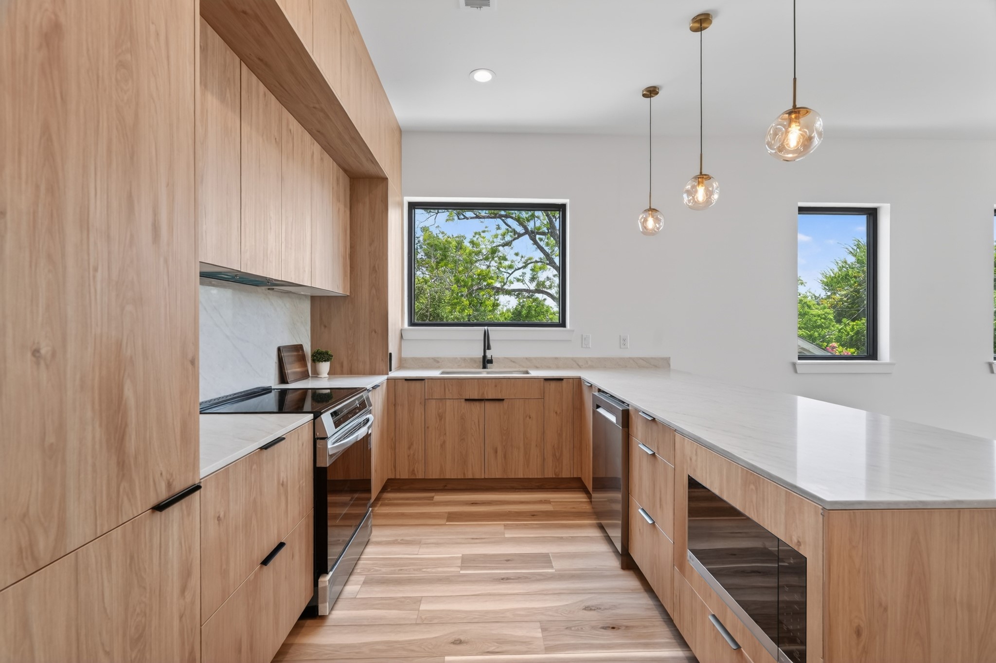 Bright, open-concept kitchen featuring sleek European-style cabinetry, elegant quartz countertops, and a modern design that seamlessly flows into the living and dining areas.