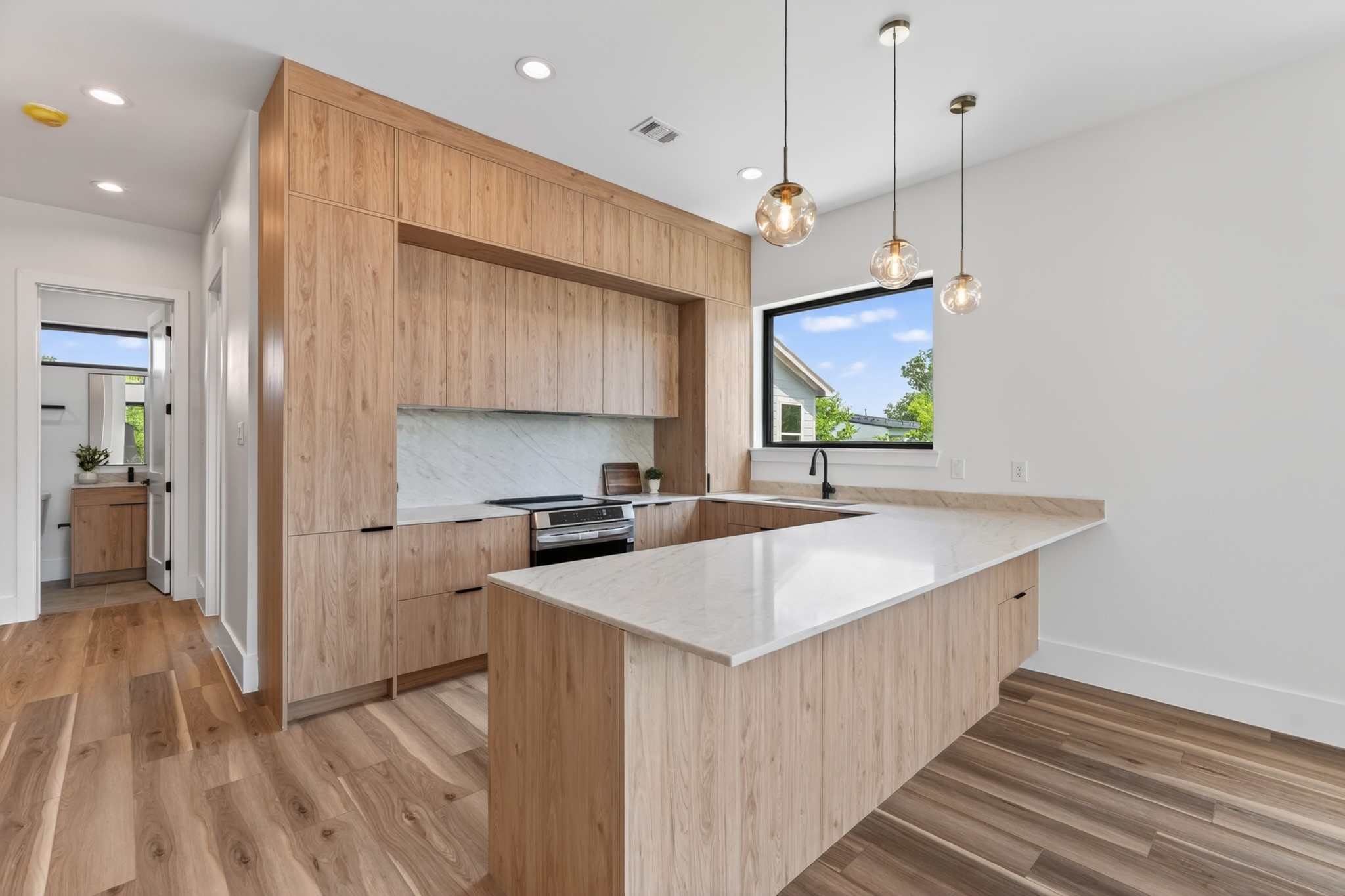 Bright, open-concept kitchen featuring sleek European-style cabinetry, elegant quartz countertops, and a modern design that seamlessly flows into the living and dining areas.