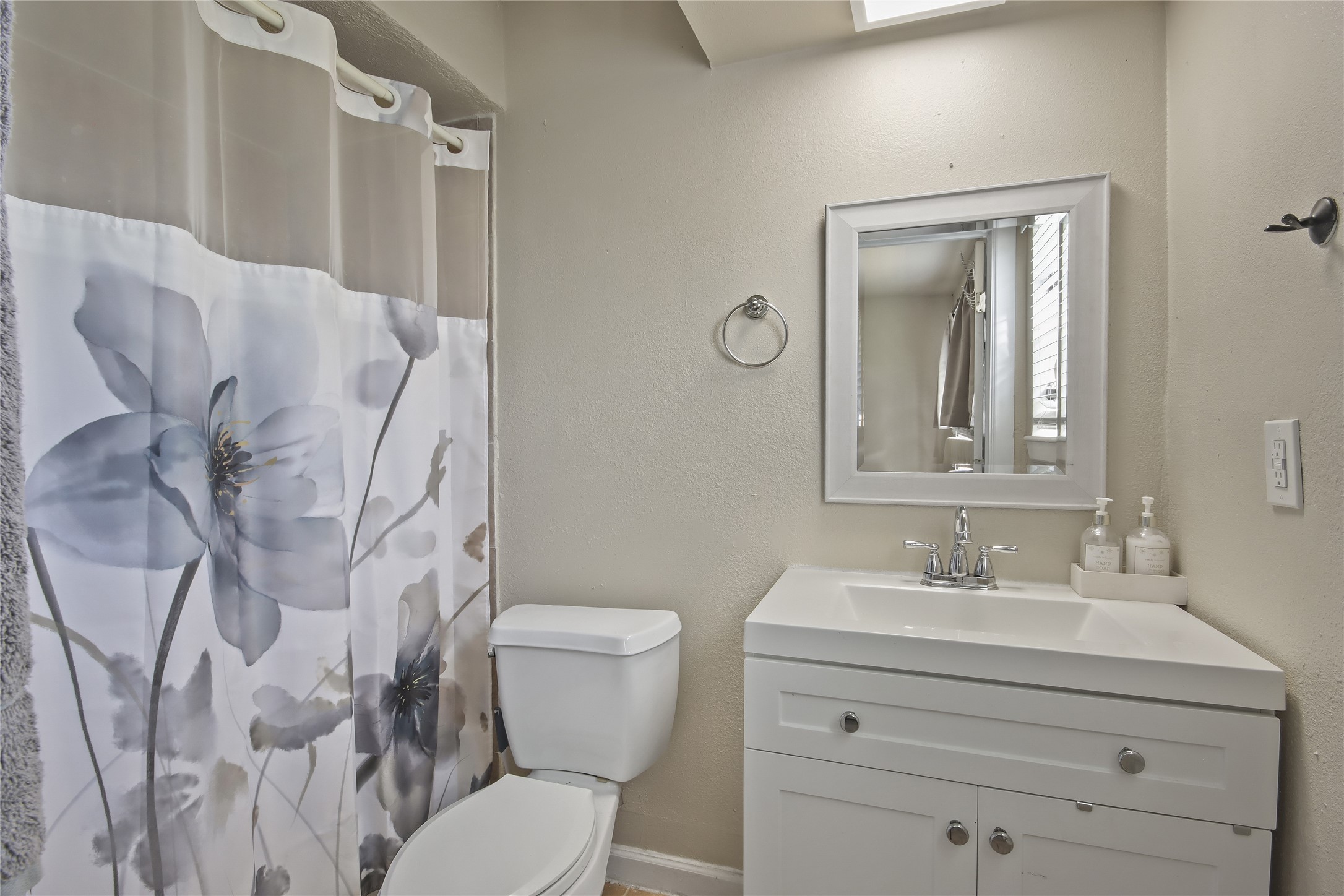 The secondary bathroom includes a tub-and-shower combination and a crisp white vanity with storage, creating a practical space.