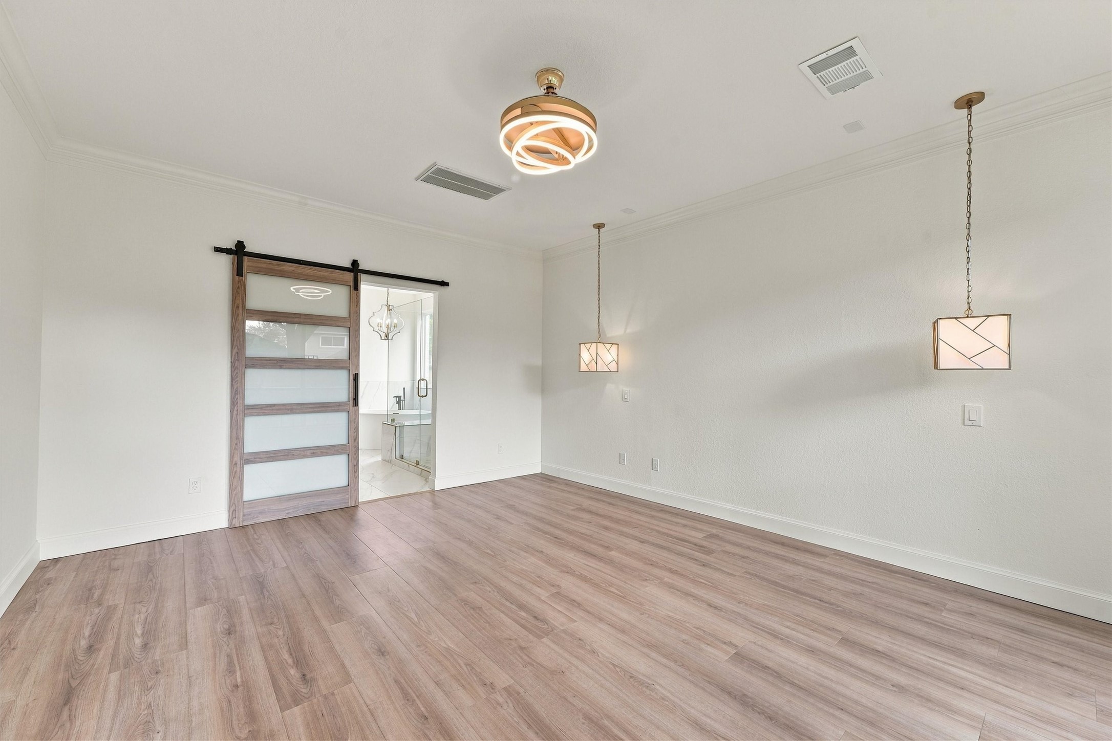 primary retreat
First-floor primary bedroom with wood flooring, sliding barn-style door, pendant lighting, and abundant natural light.