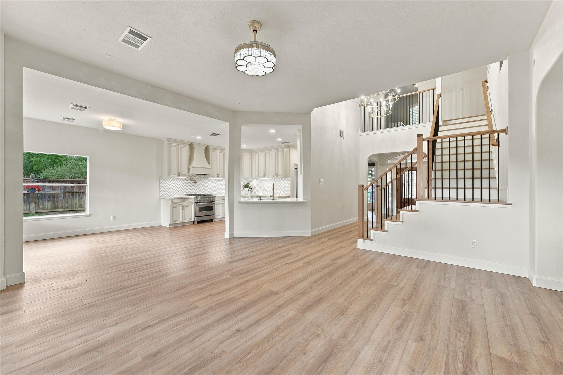 Open living area with wood flooring, abundant natural light, staircase, and open flow to the kitchen and dining areas.