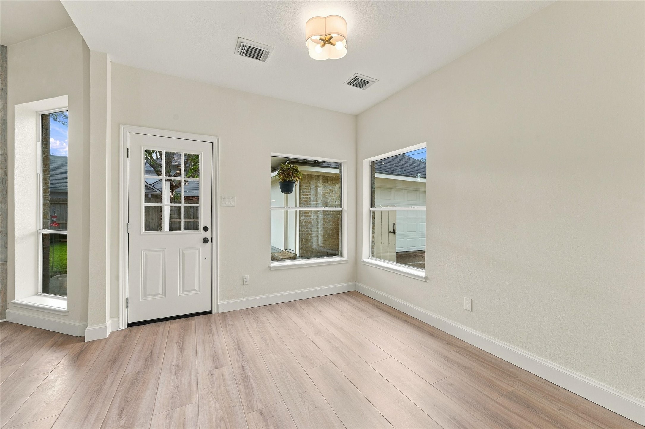 Breakfast area with wood flooring, glass-paneled door, and multiple windows for abundant natural light.