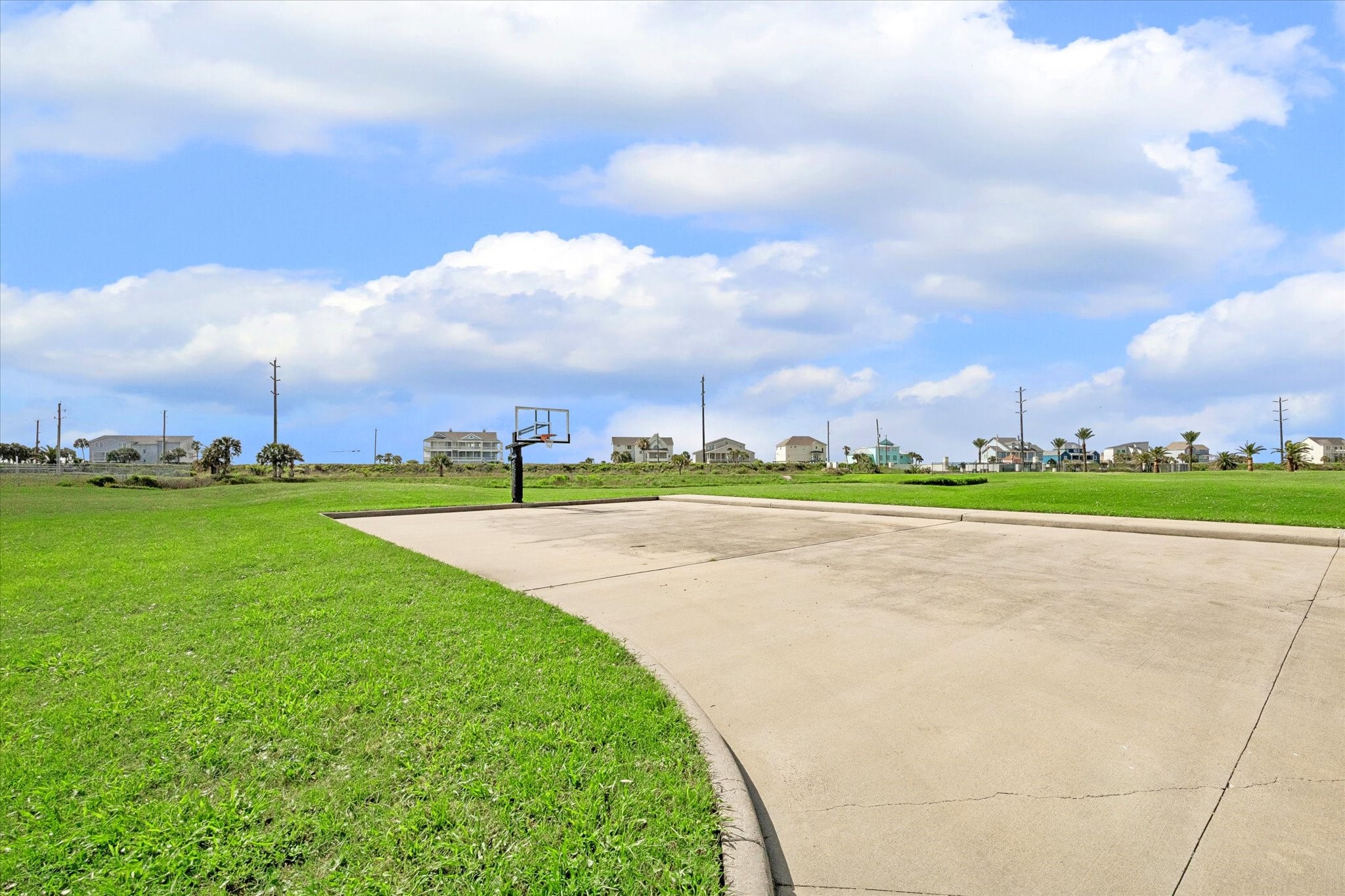 Basketball court access adds another easy way to enjoy the outdoors within Sunset Cove. Open green space and coastal homes in the distance keep the setting relaxed and neighborhood-focused.