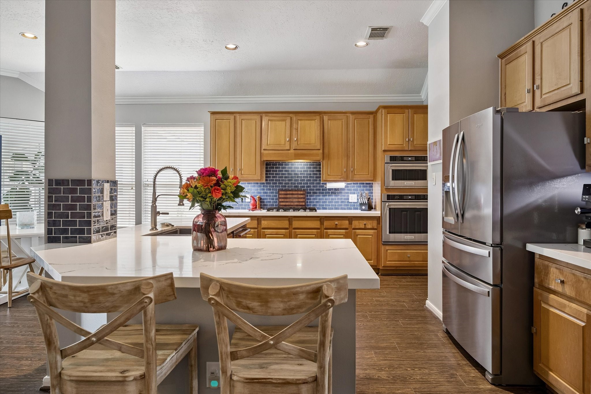 Designer kitchen featuring oversized breakfast bar, quartz countertops and KitchenAid stainless steel appliances.