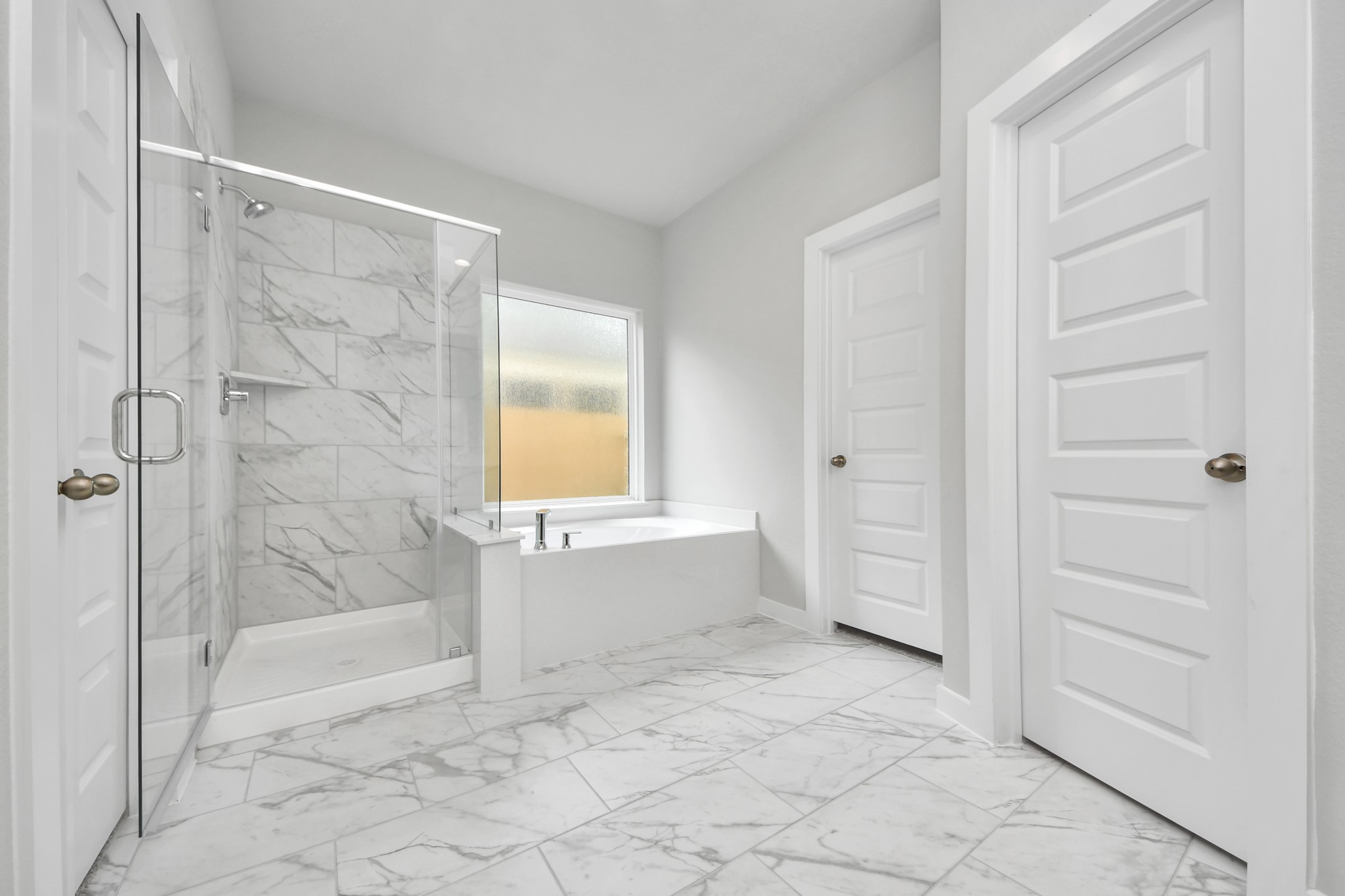 Escape to a spa-like oasis in this primary bathroom. Enjoy a walk-in shower with tile surround, a separate garden tub with custom detailing, and an elegant vanity featuring light countertops, modern hardware, and beautiful vanity lights. Experience luxury and relaxation in every detail. Sample photo of completed home with similar floor plan. Actual colors and selections may vary.
