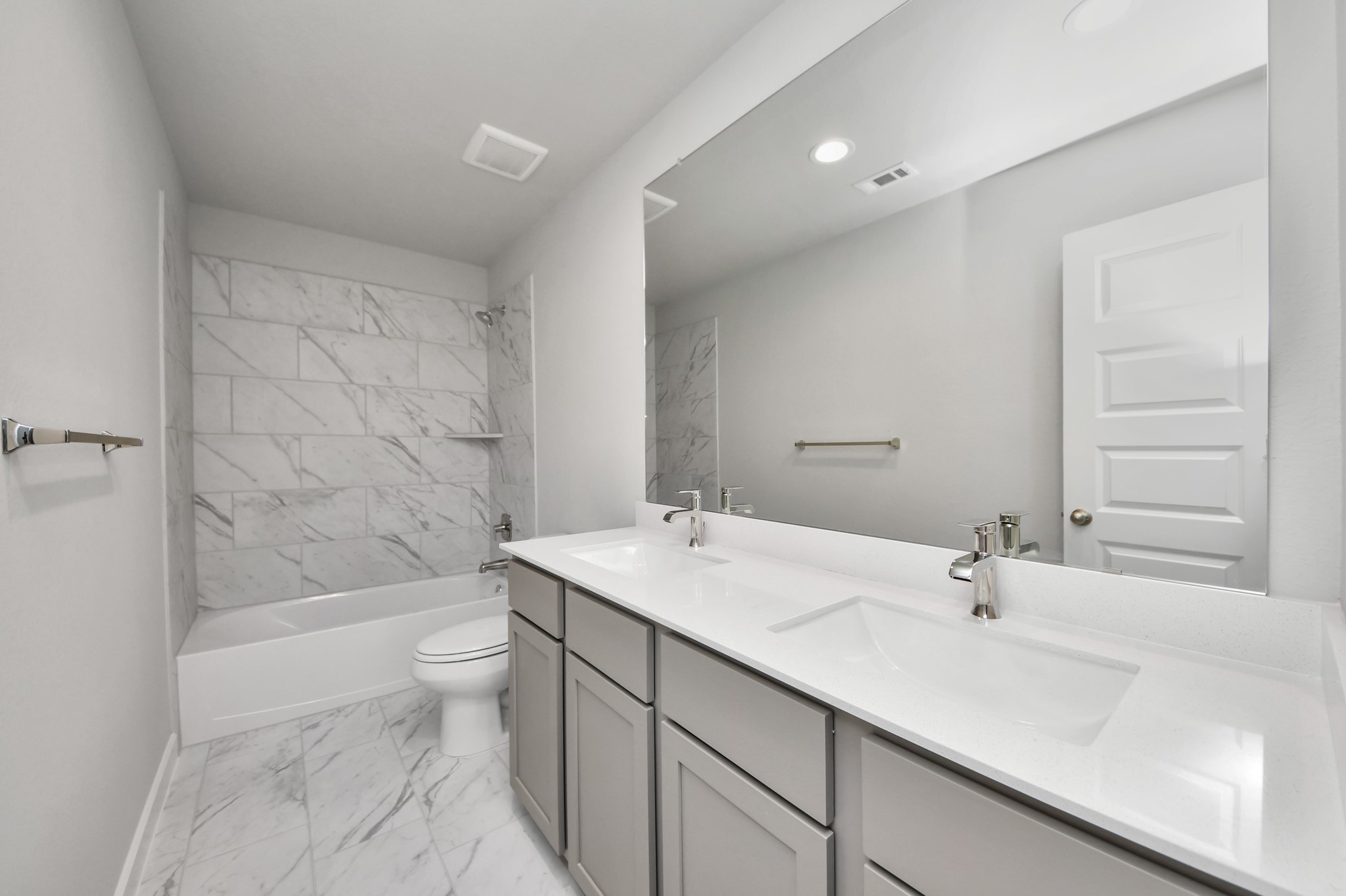 Secondary bath features tile flooring, bath/shower combo with tile surround, light stained wood cabinets, beautiful light countertop. Sample photo of completed home with similar floor plan. Actual colors and selections may vary.