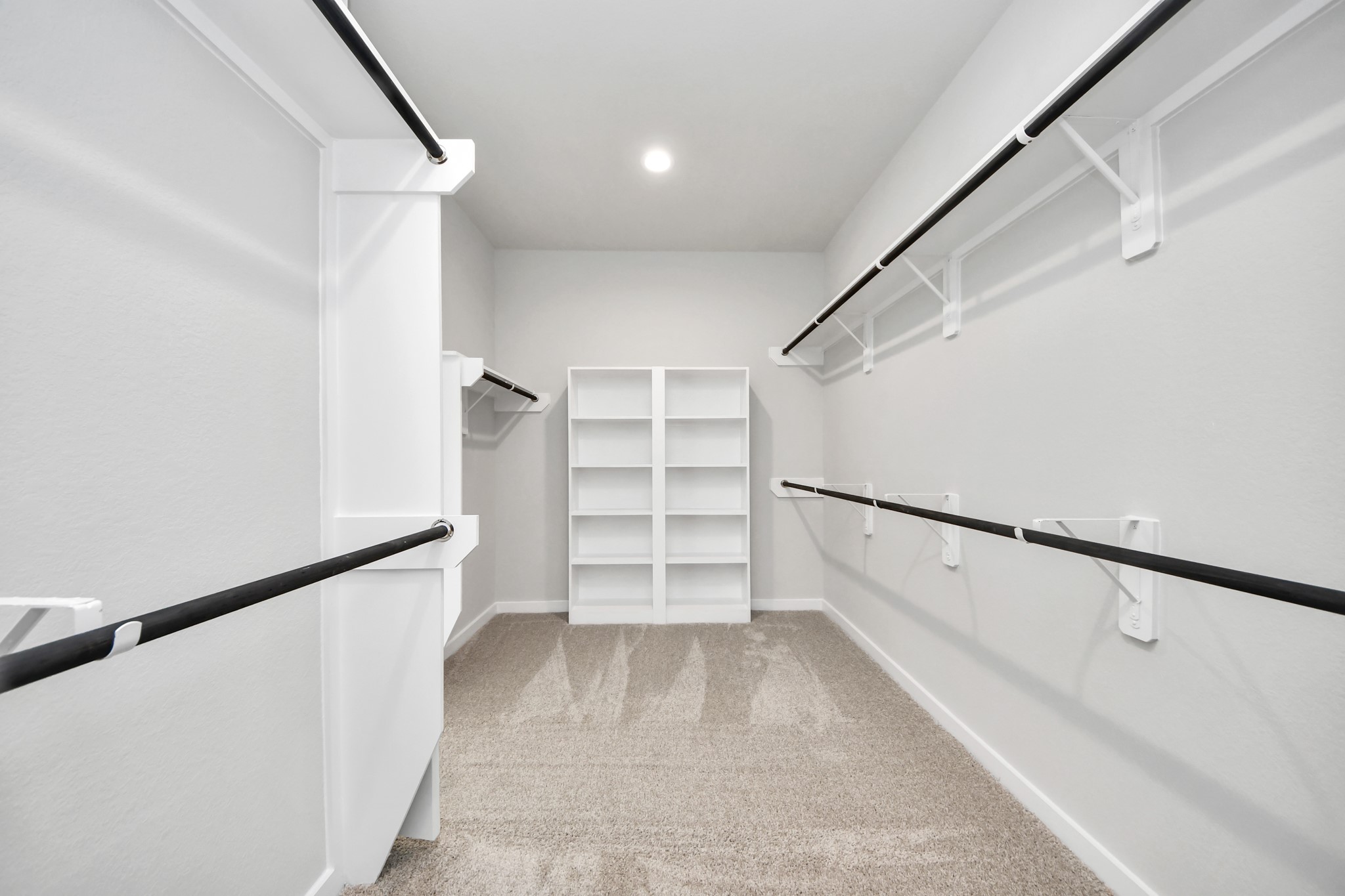 Walk-in closet that epitomizes luxury and practicality. This generously sized space features built-in shelving, offering abundant room for impeccable organization. High ceilings and recessed lighting create a bright and welcoming ambiance. Sample photo of completed home with similar floor plan. Actual colors and selections may vary.