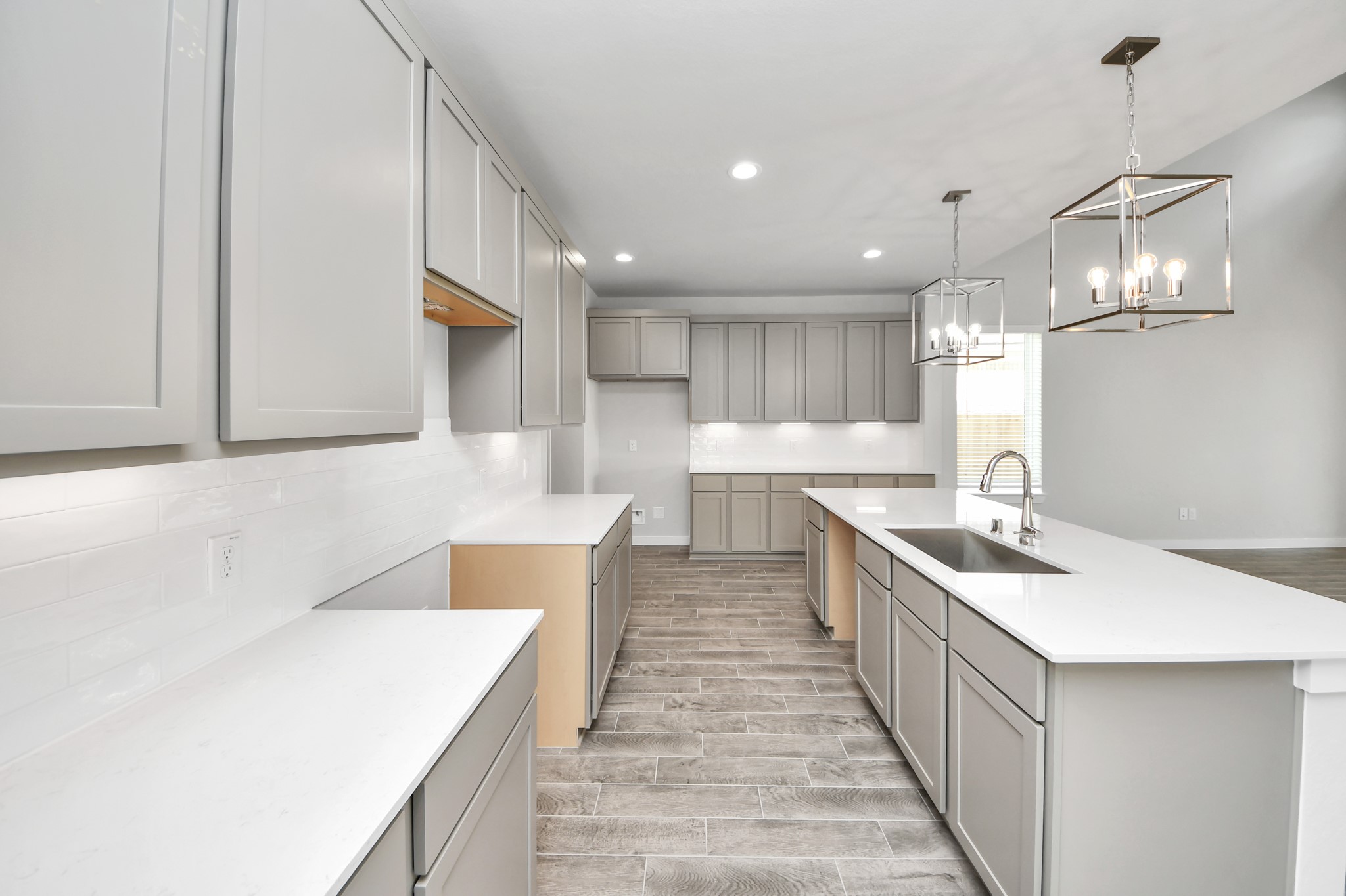 This kitchen is truly a chef's dream! This haven Boasts high ceilings, recessed & pendant lighting, stained wood cabinets, granite countertops, stainless steel appliances, a modern tile backsplash.  All of this overlooks your expansive family room, creating a perfect space for culinary delights and family gatherings. Sample photo of completed home with similar floor plan. Actual colors and selections may vary.