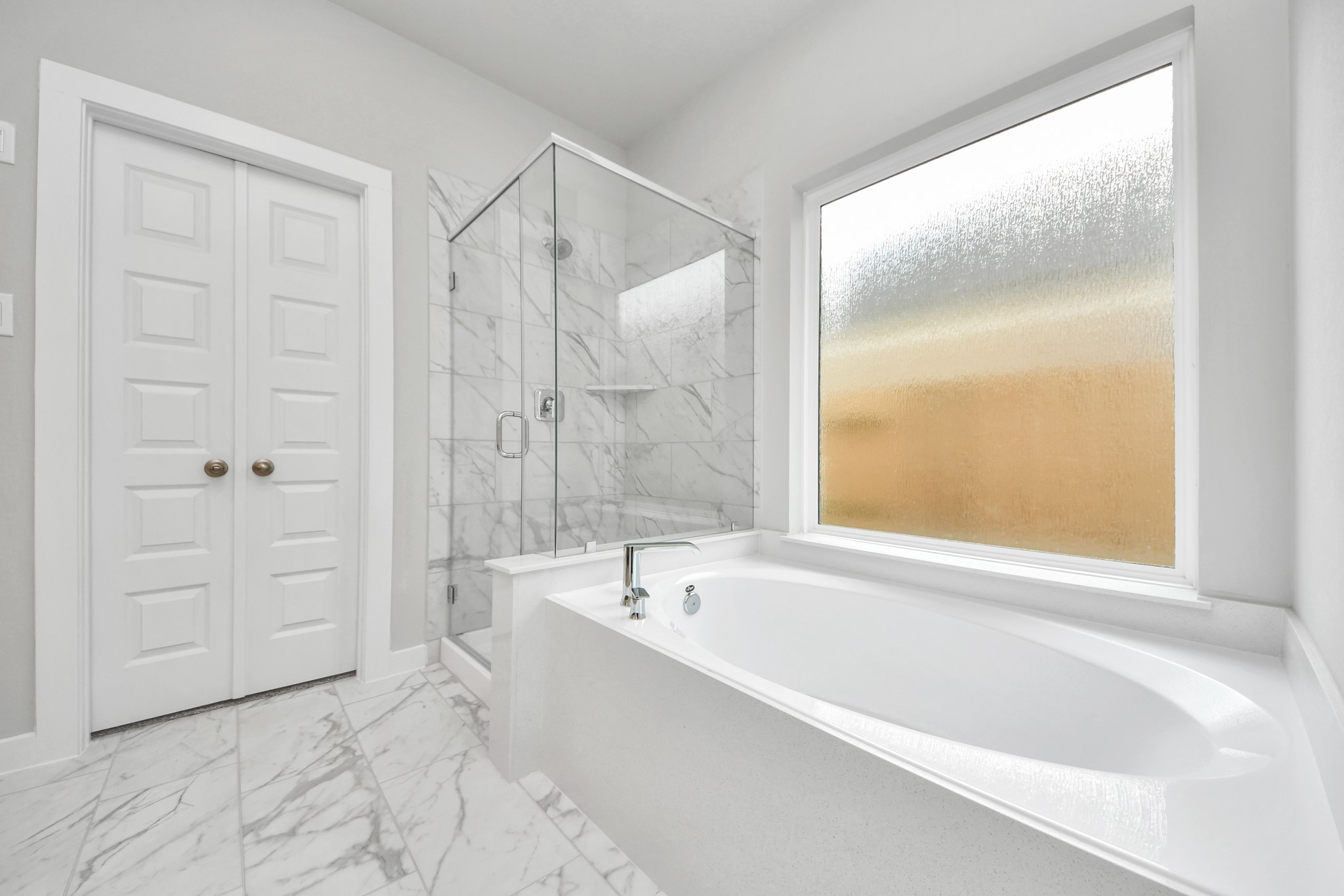 Indulge in a spa-like retreat within the confines of this primary bathroom. Delight in a spacious walk-in shower enveloped in stylish tile surround, unwind in a separate garden tub adorned with custom detailing. Sample photo of completed home with similar floor plan. Actual colors and selections may vary.