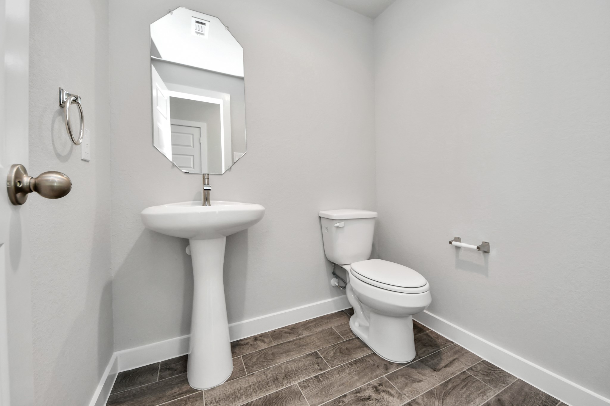 This half bathroom features a stylish pedestal sink, modern hardware, and bright recessed lighting, creating a sleek and inviting space. Sample photo of completed home with similar floor plan. Actual colors and selections may vary.