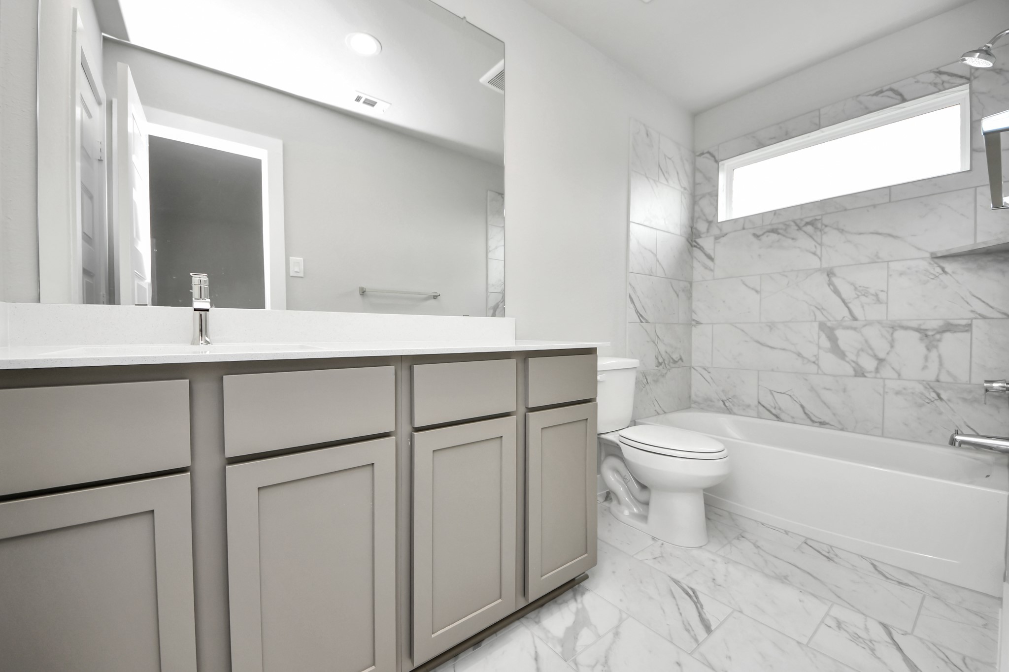 Secondary bath features tile flooring, bath/shower combo with tile surround, light stained wood cabinets, beautiful light countertop. Sample photo of completed home with similar floor plan. Actual colors and selections may vary.