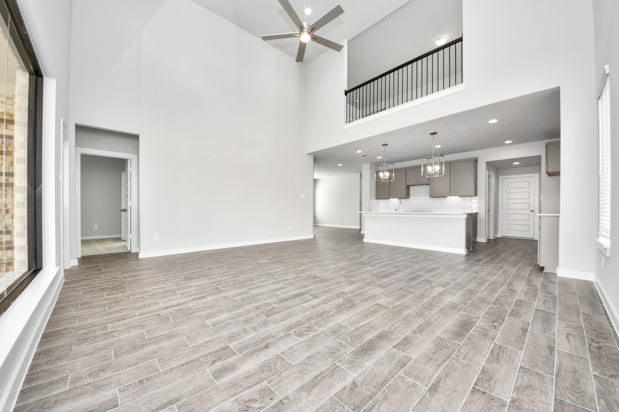 Relax and unwind in this inviting family room, illuminated by abundant natural light streaming in through tall windows, complemented by high ceilings and stunning flooring. Stay comfortable year-round with the gentle breeze from the ceiling fan, creating the perfect atmosphere for family gatherings. Sample photo of completed home with similar floor plan. Actual colors and selections may vary.