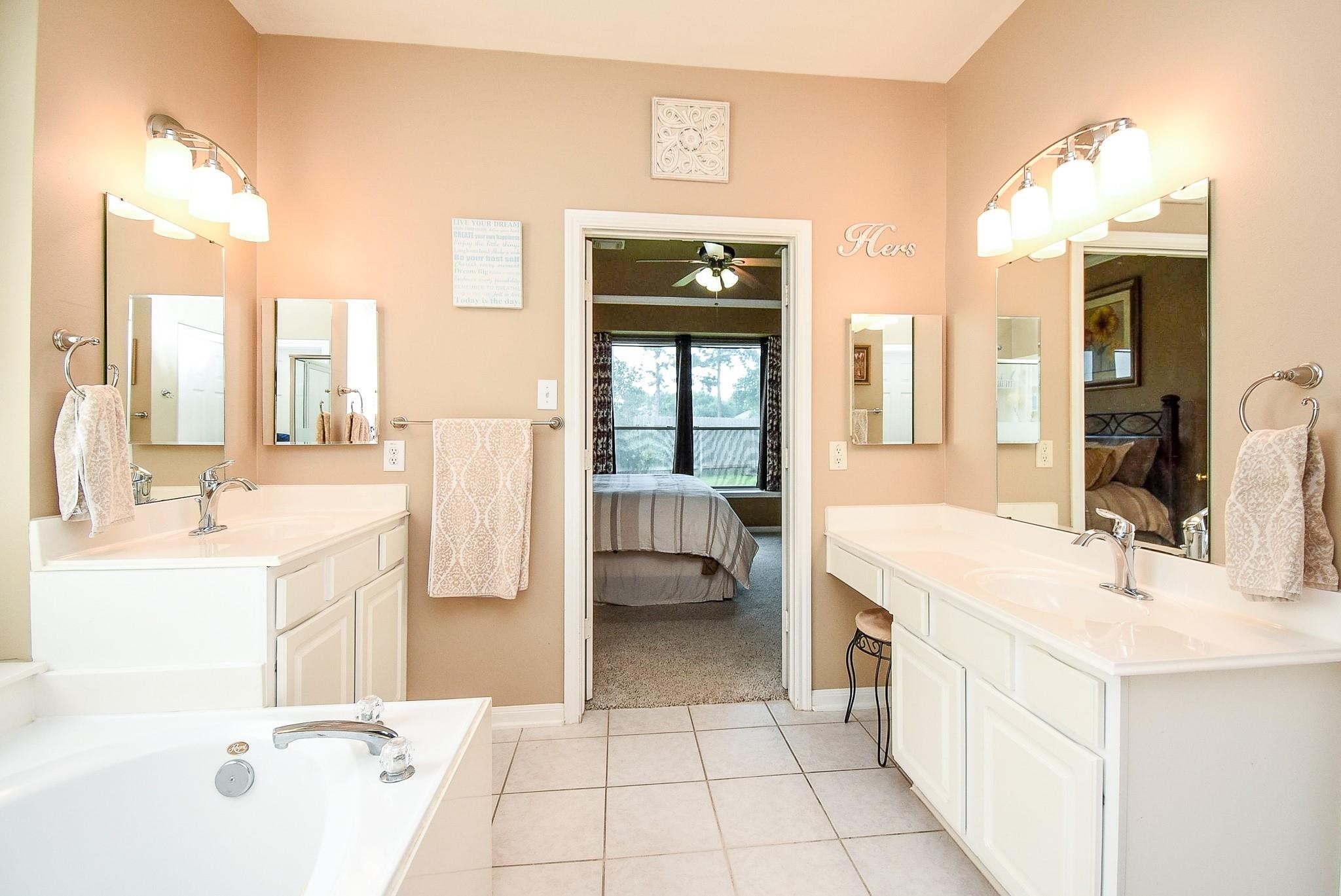 Luxurious primary bathroom with dual vanities and a spacious his-and-hers closets.