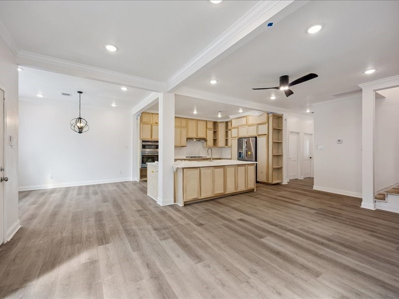 Kitchen & Living Area  Expansive open layout with wide-plank flooring, recessed lighting, crown molding, and abundant natural light. Home is currently under renovation and not yet complete.