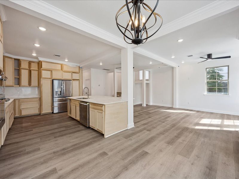 Kitchen & Living Area  Expansive open layout with wide-plank flooring, recessed lighting, crown molding, and abundant natural light. Home is currently under renovation and not yet complete.