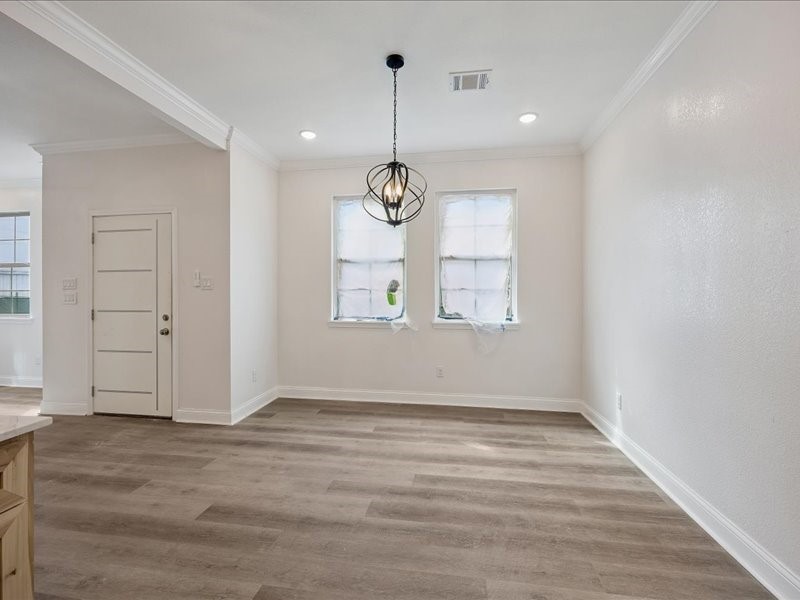 Dining Area  Dedicated dining area positioned just off the kitchen with wide-plank flooring, crown molding, contemporary lighting, and natural light. Additional finishing touches remain in progress.