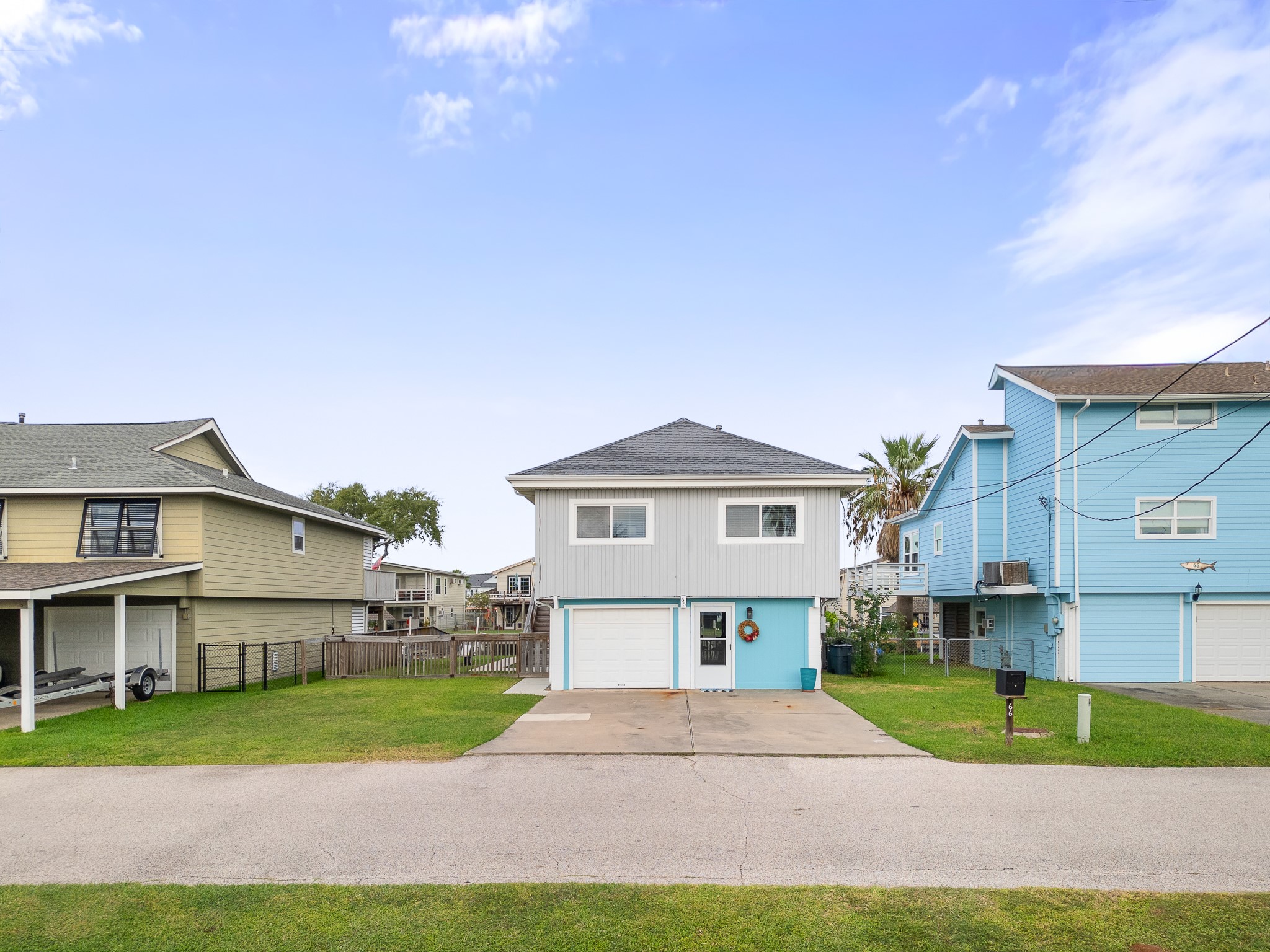 Front exterior view with driveway, attached garage and fenced side yard.