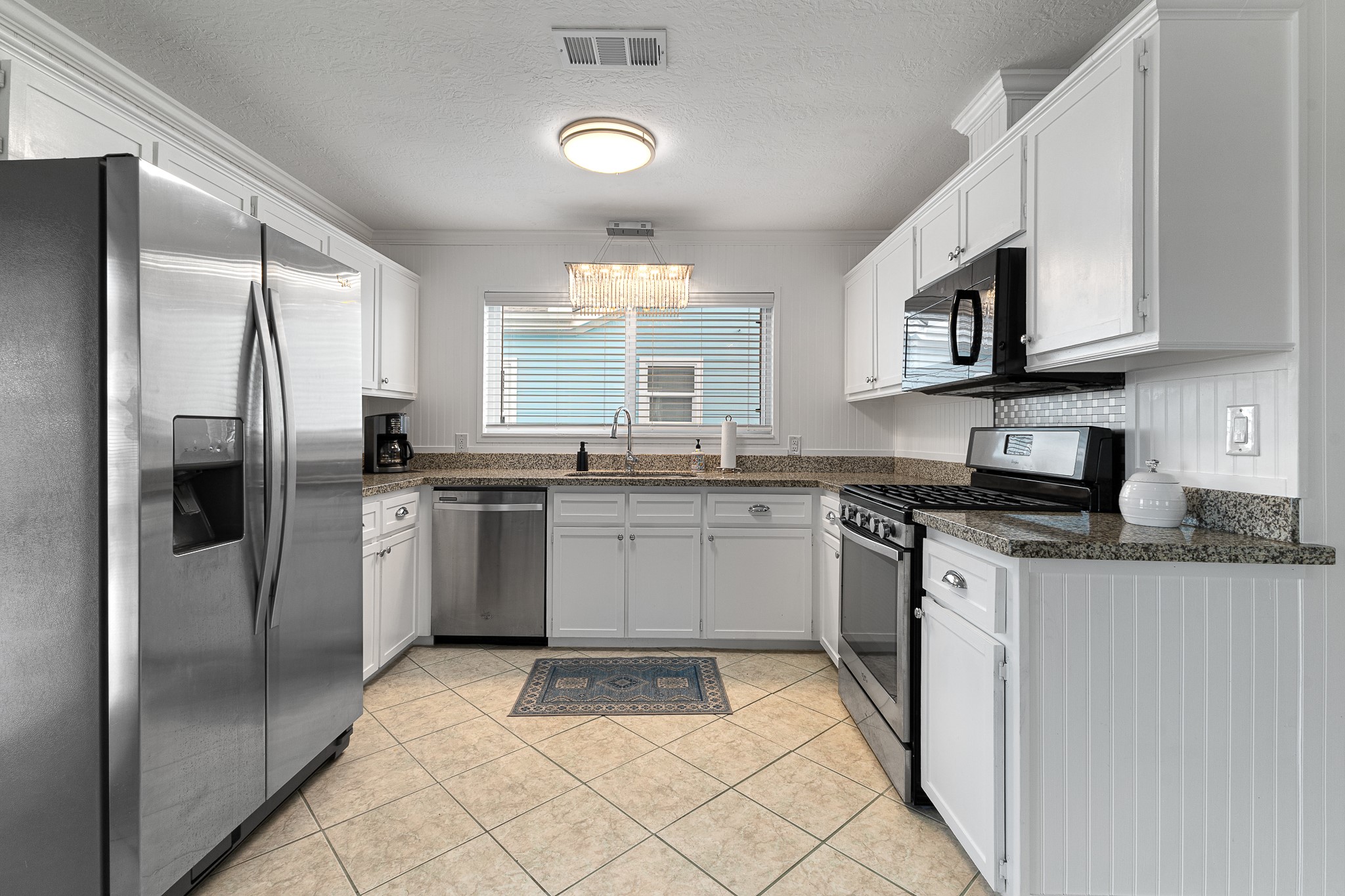 Bright kitchen with white cabinetry, granite countertops and stainless appliances. Bright kitchen with white cabinetry, granite countertops and stainless appliances.