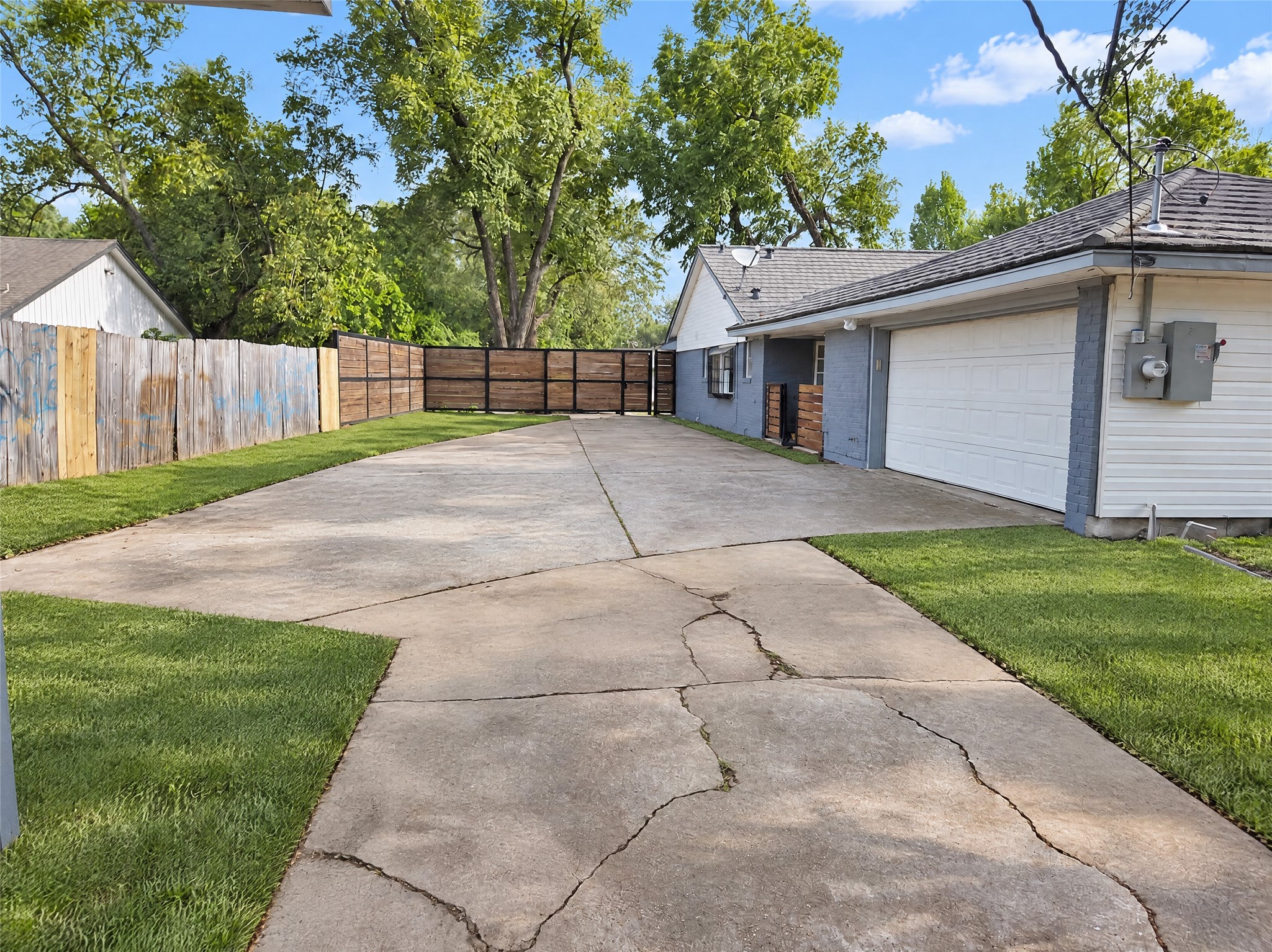 An oversized concrete driveway provides abundant off-street parking, room for recreational vehicles or guests, and leads to an attached garage alongside a secure, gated rear perimeter.