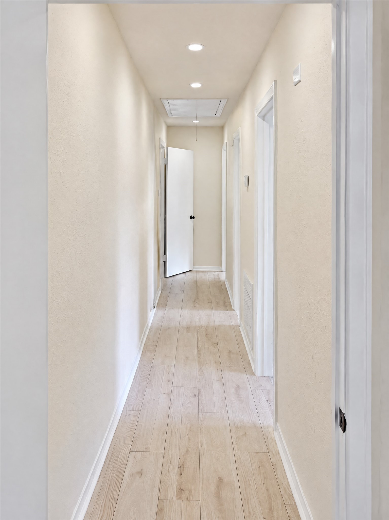 Move down the wide, well-lit hallway that leads to the private bedroom wing, offering a thoughtful floor plan that separates restful retreats from the central entertainment hubs.