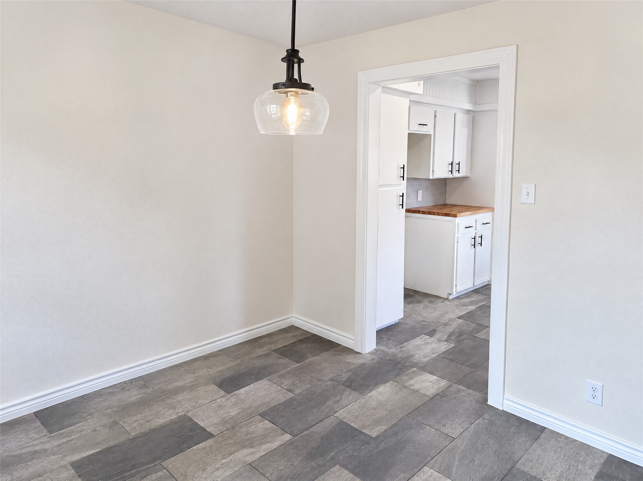 Situated right off the kitchen, this dedicated breakfast nook features stylish pendant lighting, low-maintenance tile flooring, and a large window overlooking the outdoor green space.