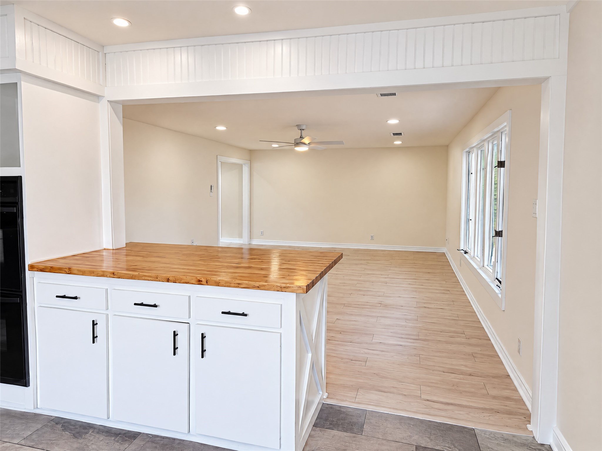 The open layout effortlessly bridges the living room and kitchen. The peninsula island with warm butcher block countertops provides convenient barstool seating and keeps conversation flowing between the cook and guests.