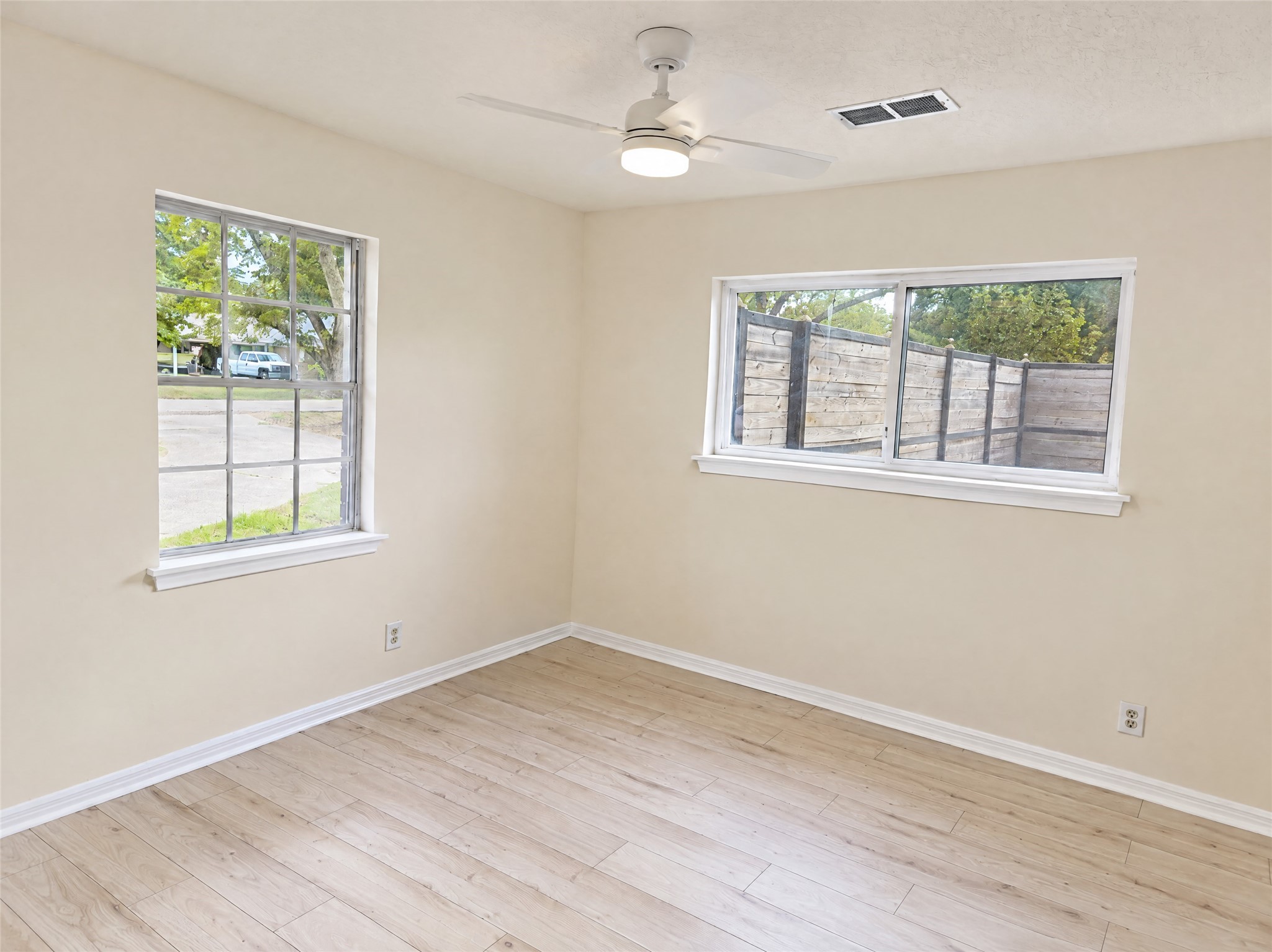 Generously sized with dual windows that welcome plenty of natural breeze and light, this bedroom is complete with durable wood-look flooring, neutral paint, and an updated ceiling fanideal for family, guests, or a dedicated home office.