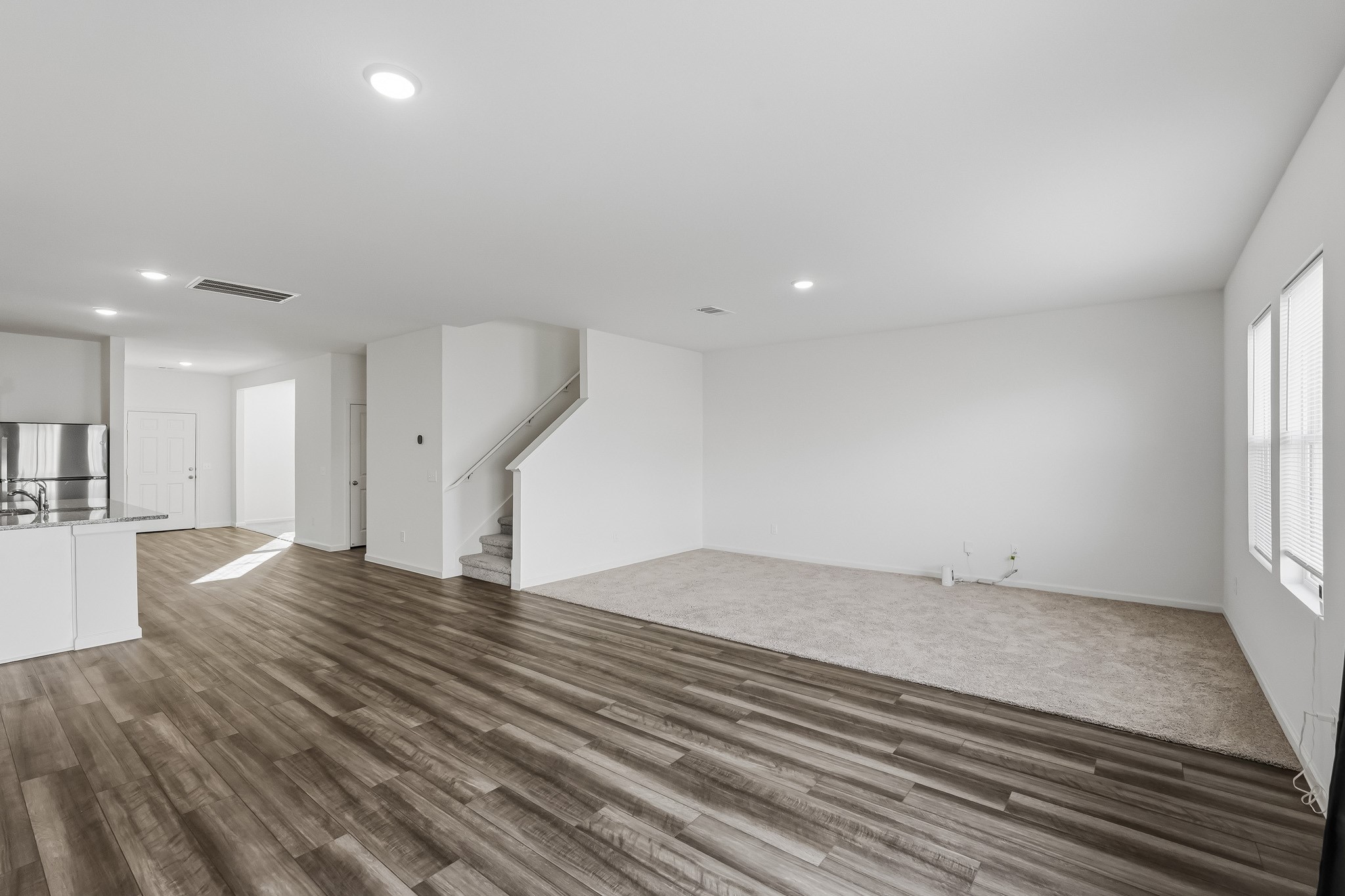 Rich wood-look flooring flows throughout the main gathering space, beautifully contrasting with crisp white walls and recessed ceiling lighting. Rich wood-look flooring flows throughout the main gathering space, beautifully contrasting with crisp white walls and recessed ceiling lighting.