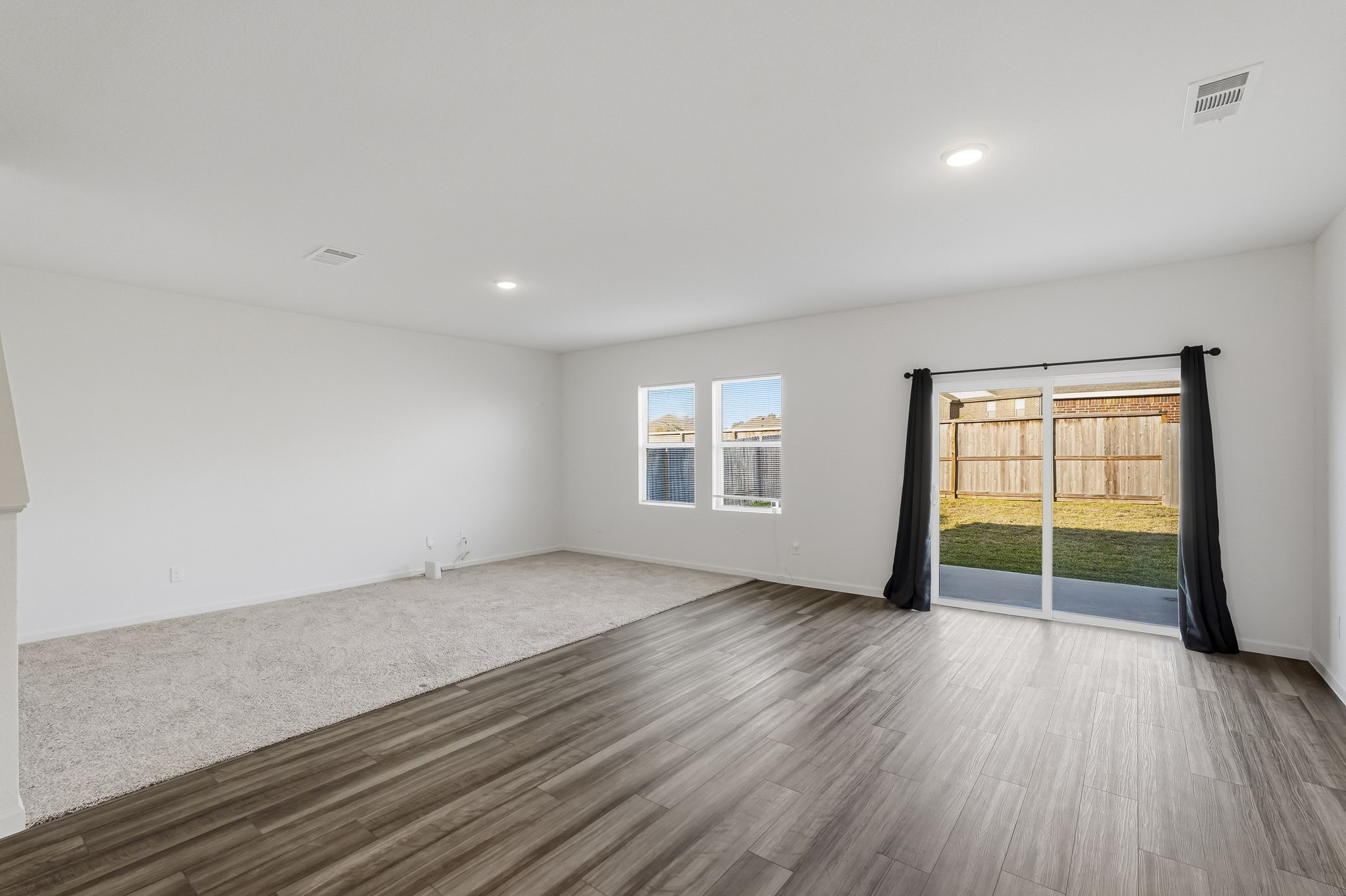 This expansive open-concept living area features a bright, airy layout designed for comfortable everyday living and effortless entertaining. Two generously sized windows welcome abundant natural light, while large sliding glass doors provide direct access to the backyard and patio, creating a seamless connection between indoor and outdoor living. This expansive open-concept living area features a bright, airy layout designed for comfortable everyday living and effortless entertaining. Two generously sized windows welcome abundant natural light, while large sliding glass doors provide direct access to the backyard and patio, creating a seamless connection between indoor and outdoor living.