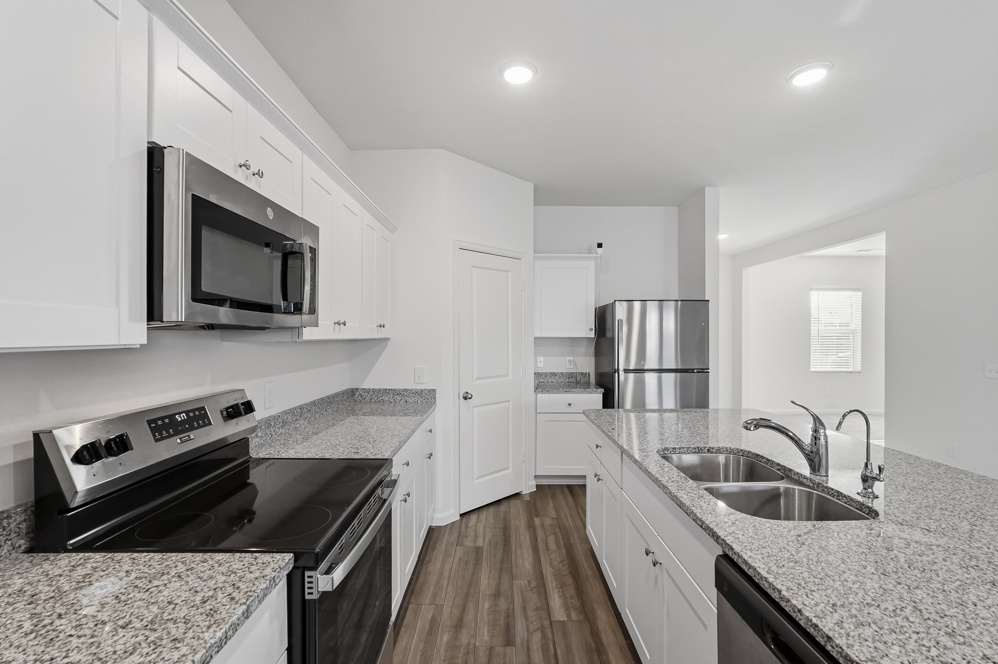 This bright and modern kitchen features a thoughtfully designed layout with crisp white Shaker-style cabinetry, beautiful speckled granite countertops, and sleek stainless steel appliances. A convenient walk-in pantry provides additional storage space, helping keep the kitchen organized and everyday essentials easily accessible. With ample counter space, abundant cabinetry, and an open connection to the adjoining living areas, this kitchen combines style, functionality, and everyday convenience. This bright and modern kitchen features a thoughtfully designed layout with crisp white Shaker-style cabinetry, beautiful speckled granite countertops, and sleek stainless steel appliances. A convenient walk-in pantry provides additional storage space, helping keep the kitchen organized and everyday essentials easily accessible. With ample counter space, abundant cabinetry, and an open connection to the adjoining living areas, this kitchen combines style, functionality, and everyday convenience.