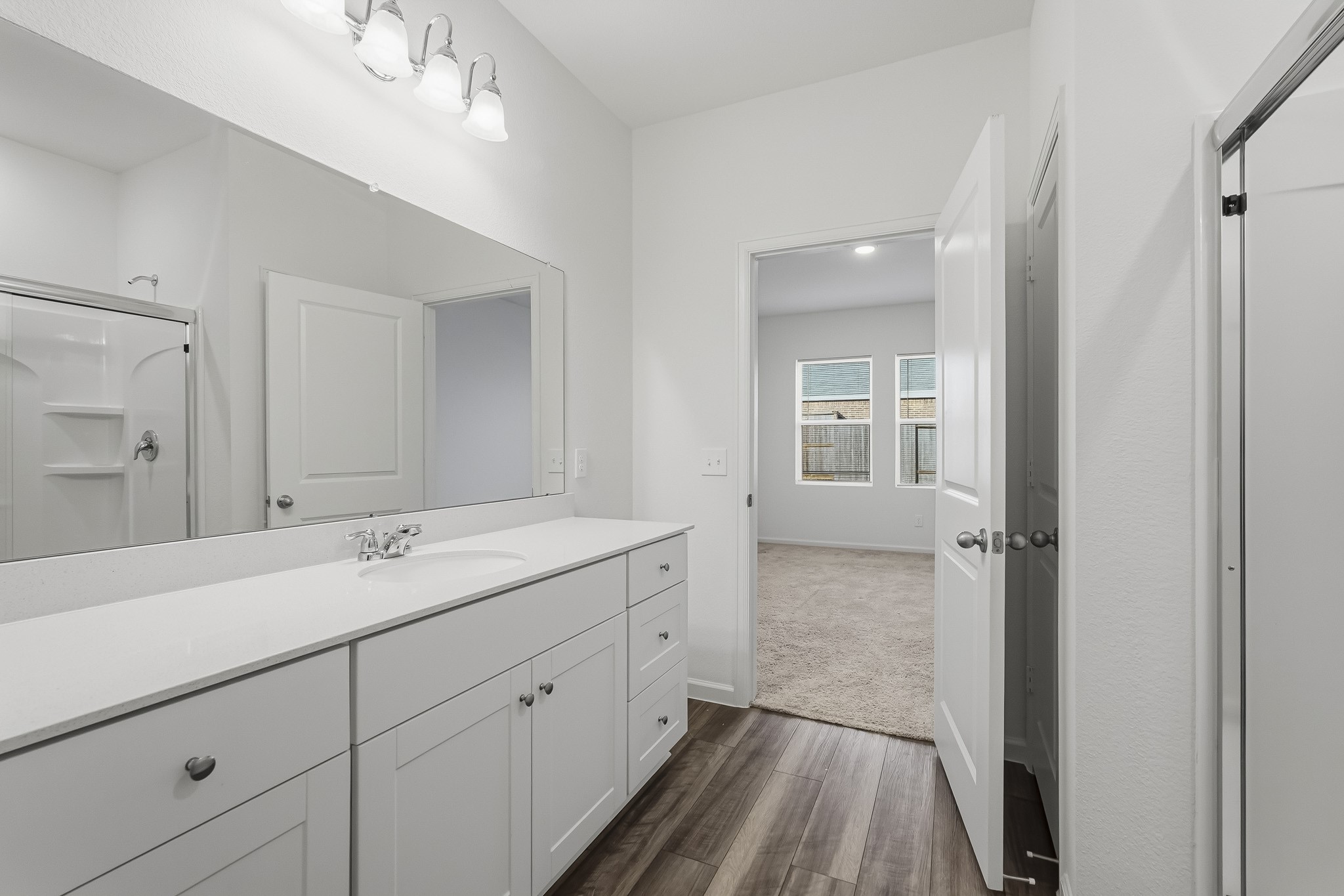 An impressive oversized wall-mounted mirror extends across the vanity, enhancing the room's open and airy atmosphere.