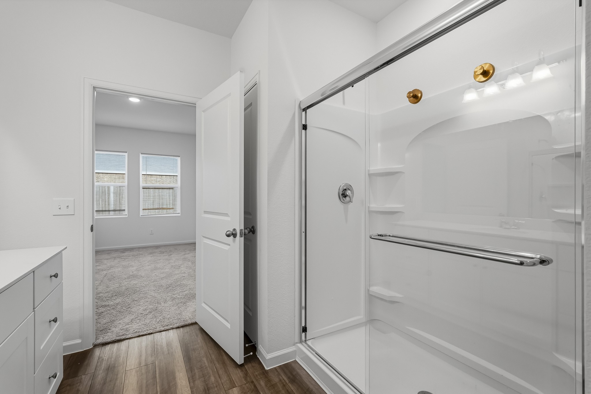 The glass-enclosed walk-in shower features sleek sliding doors and built-in shelving for added convenience.