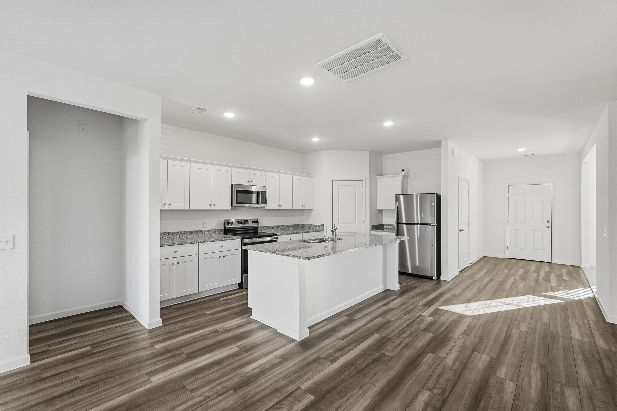 This bright and spacious open-concept kitchen features a clean, modern design with crisp white Shaker-style cabinetry, speckled granite countertops, and sleek stainless steel appliances. A generously sized center island provides additional counter space, a built-in sink, and a convenient area for meal preparation or casual dining. This bright and spacious open-concept kitchen features a clean, modern design with crisp white Shaker-style cabinetry, speckled granite countertops, and sleek stainless steel appliances. A generously sized center island provides additional counter space, a built-in sink, and a convenient area for meal preparation or casual dining.