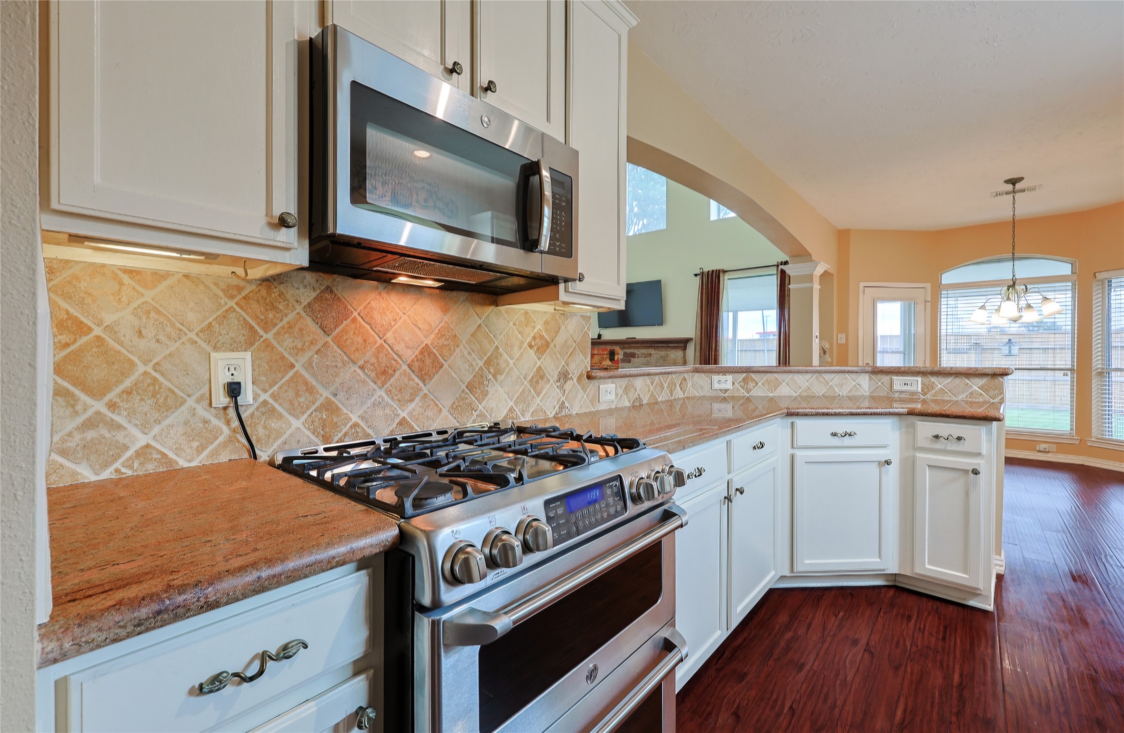 Gas range with granite counters,.undermount lighting, tumbled marble backsplash