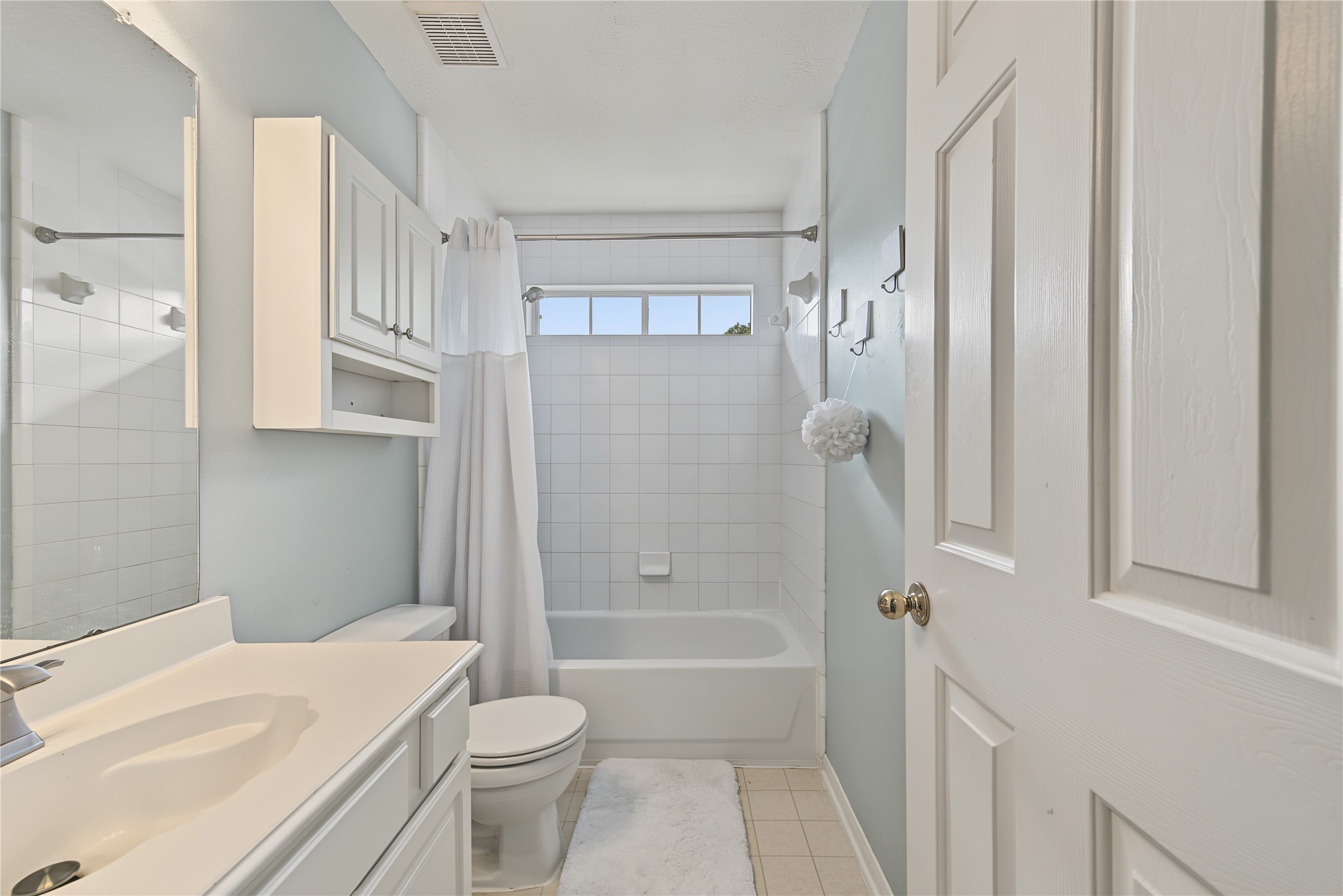Bright guest bath with a tiled tub/shower combination and natural light