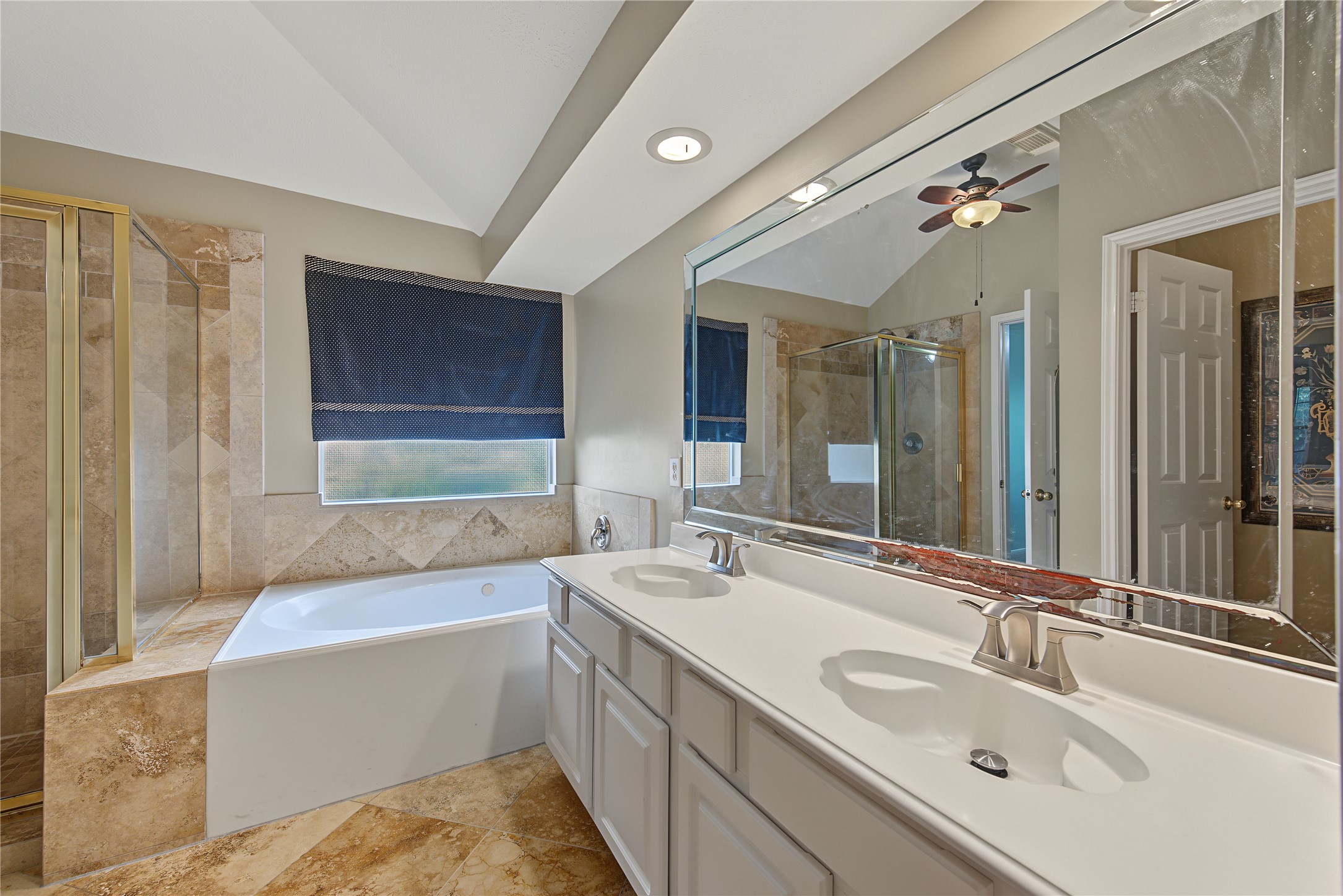 Primary en-suite bath with dual sinks, a jetted tub, and separate glass-enclosed shower