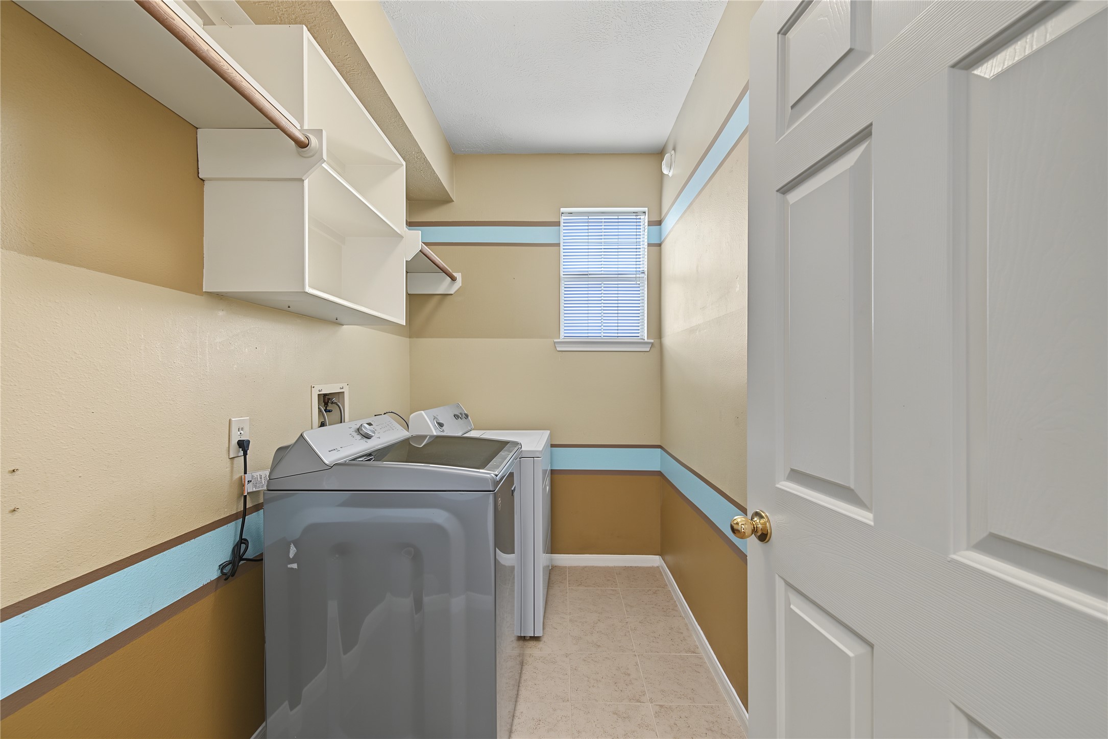 Utility room with built-in shelving, hanging space, and natural light