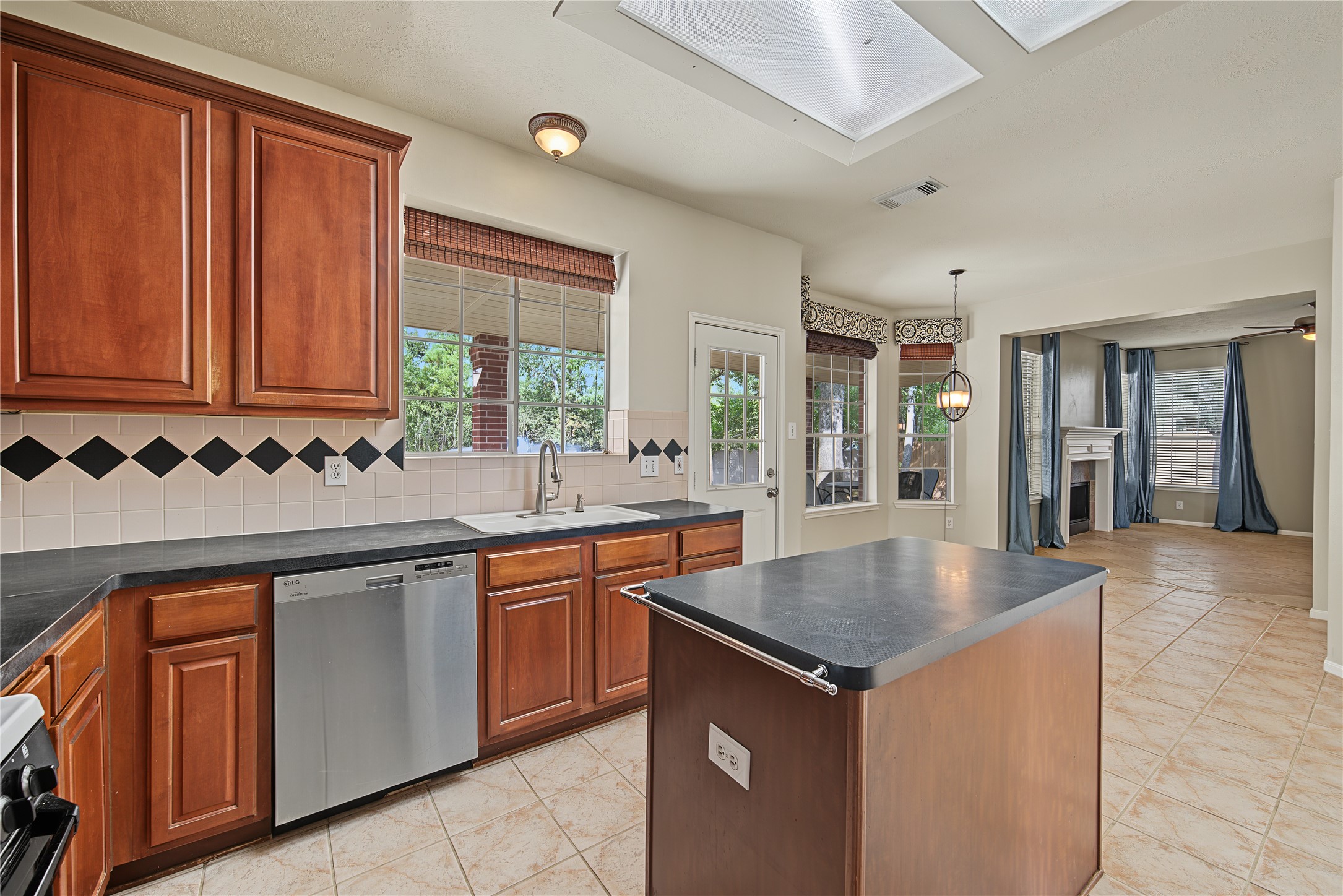 Island kitchen opens to the breakfast area, with the family room visible at the far end and backyard views through the windows
