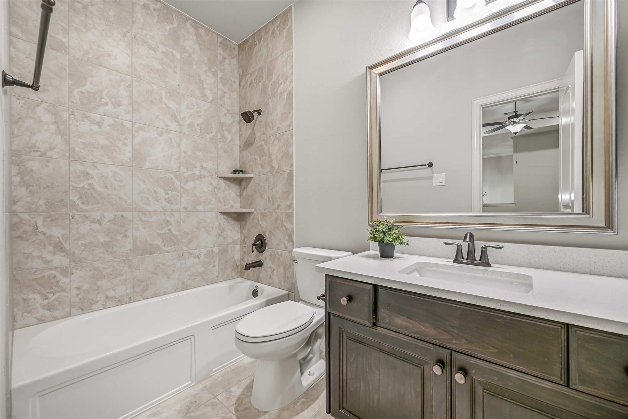 Conveniently located off the game room, this full bathroom serves both the game room & adjoining secondary bedroom. Features include a quartz-topped vanity, rectangular sink, stained wood cabinetry, framed mirror & tub/shower combination with a tiled surround.