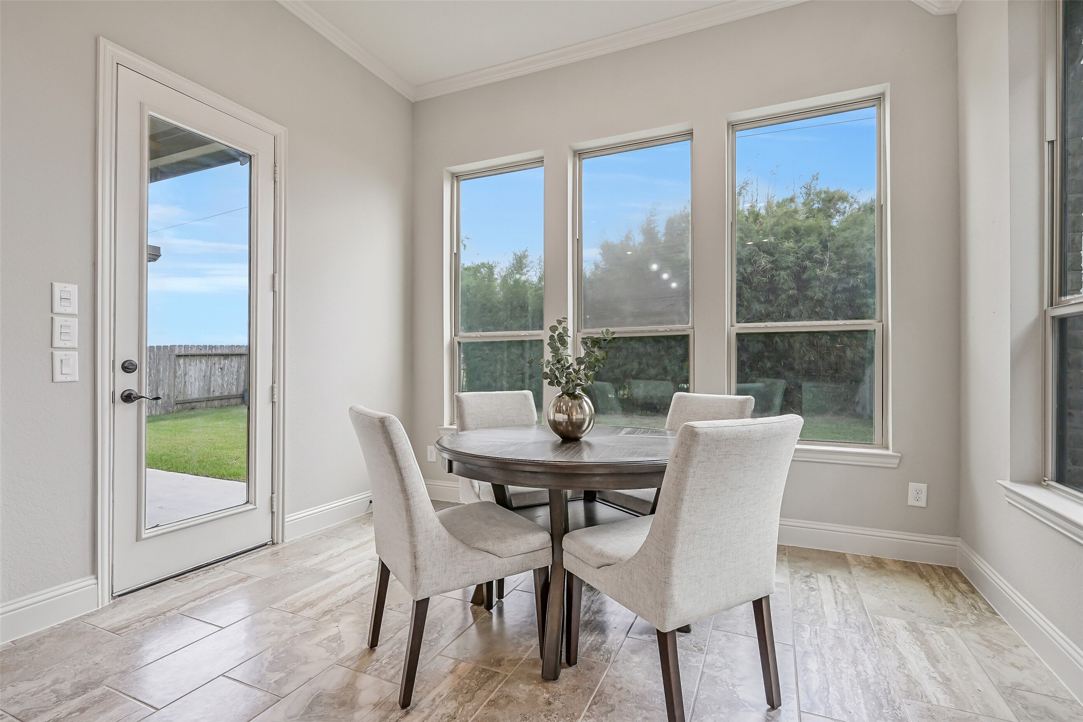 Tucked beside the kitchen, the cheerful breakfast room is surrounded by windows overlooking the backyard & established bamboo landscaping. Stone-look tile flooring, crown molding & a full-glass door leading to the covered patio complete this inviting space.