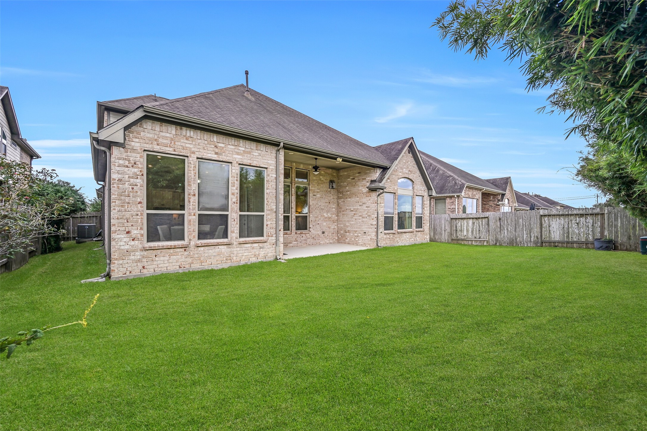 Looking back toward the home, you'll appreciate the attractive brick exterior, abundant windows & covered patio tucked between the family room and primary suite. The spacious fenced backyard offers plenty of grassy room for pets, play, gardening or future outdoor plans!