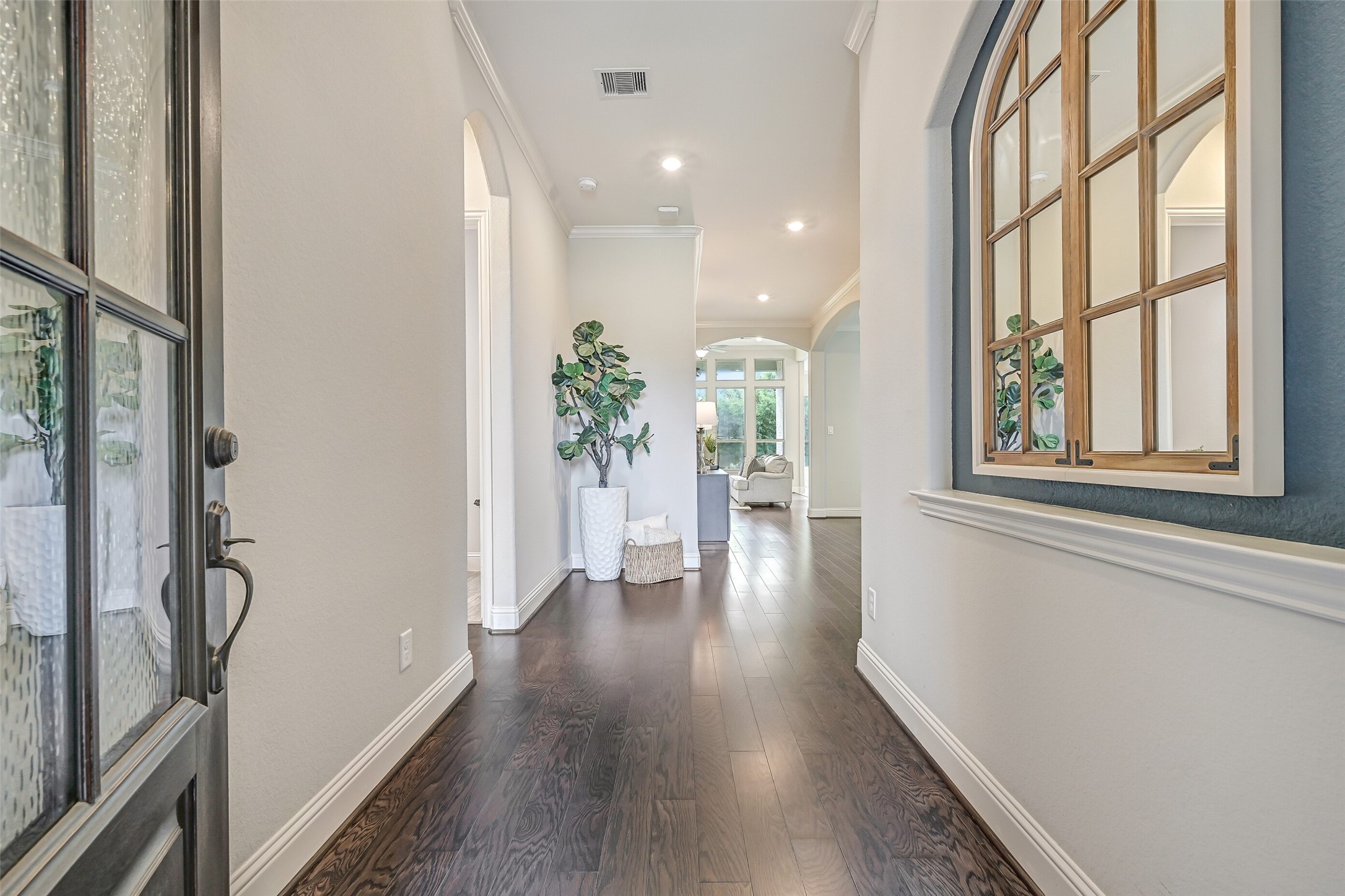 Step through the 8' Flemish glass front door into a dramatic two-story foyer with a 20' ceiling, rich luxury vinyl plank flooring & fresh neutral walls. Arched openings and a decorative interior window set against a blue-gray accent wall add character as your eye travels toward the family room.