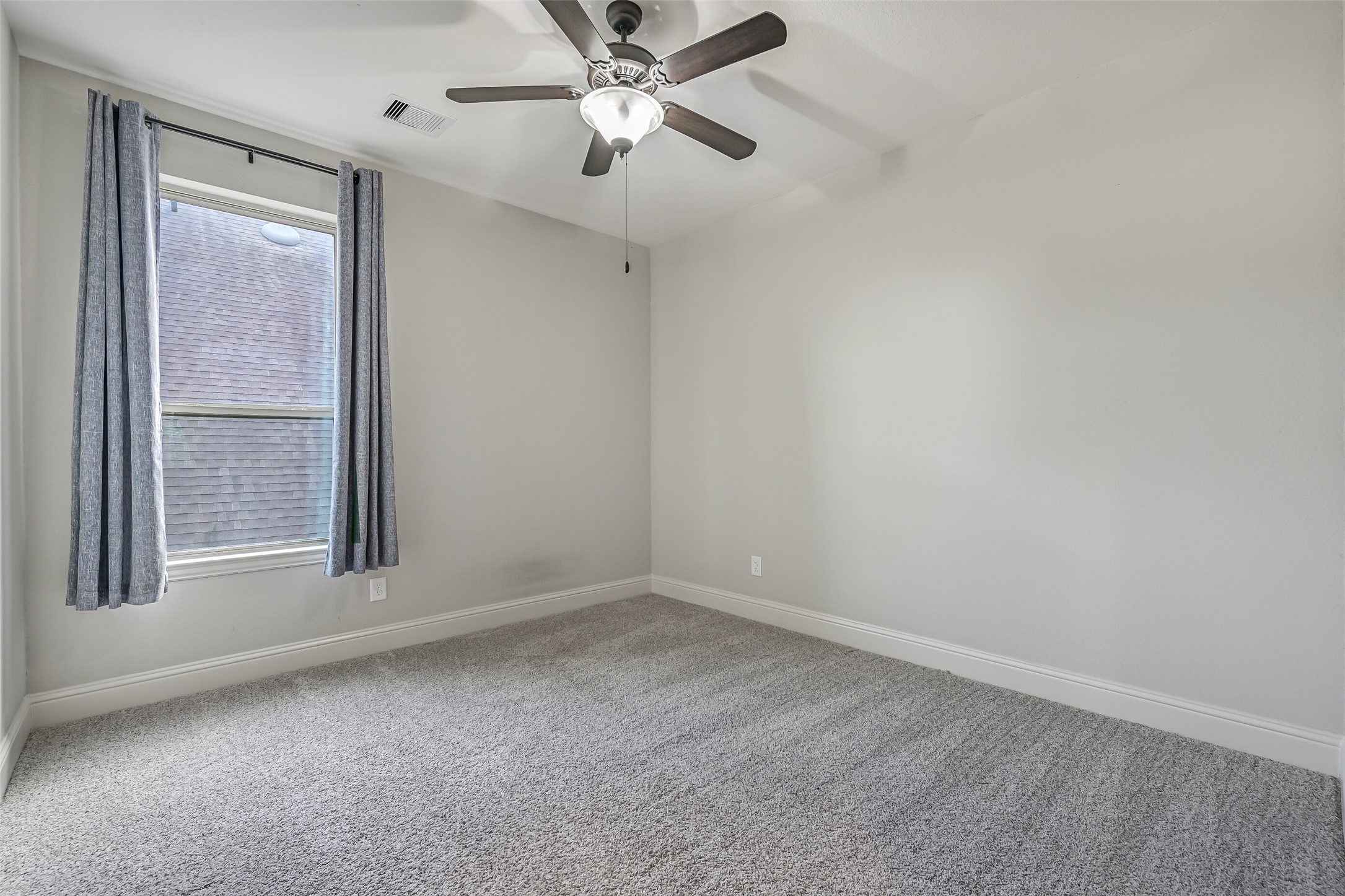 Just off the game room, this secondary bedroom features plush carpeting, neutral walls, a lighted ceiling fan & a side-facing window with draperies. A walk-in closet provides plenty of storage, with a shared full bathroom conveniently located down the hall.