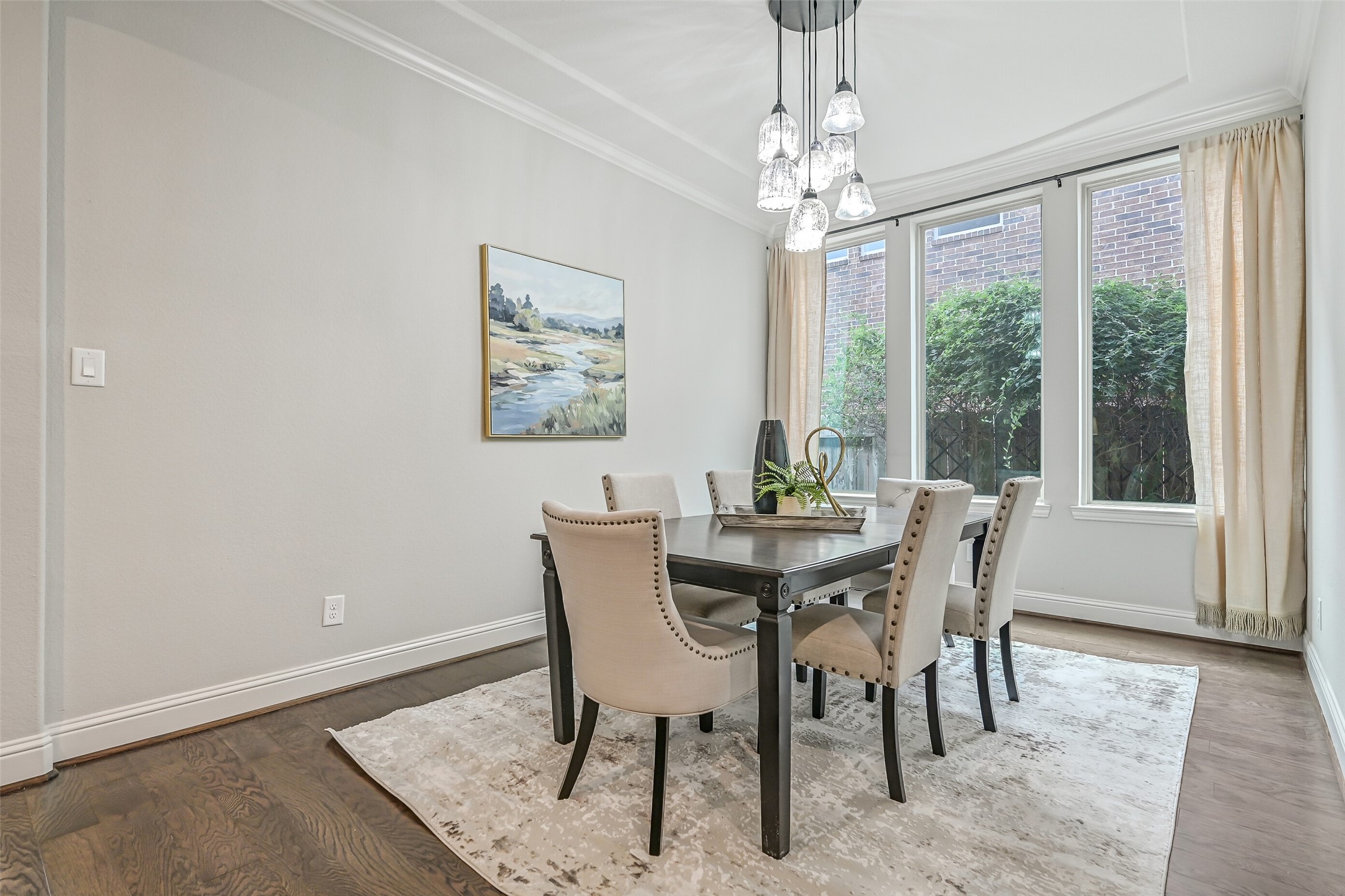 Just off the foyer, the formal dining room features rich luxury vinyl plank flooring, crown molding, a custom cascading glass chandelier & a trio of windows overlooking the side landscaping. Plenty of room to gather around the table!