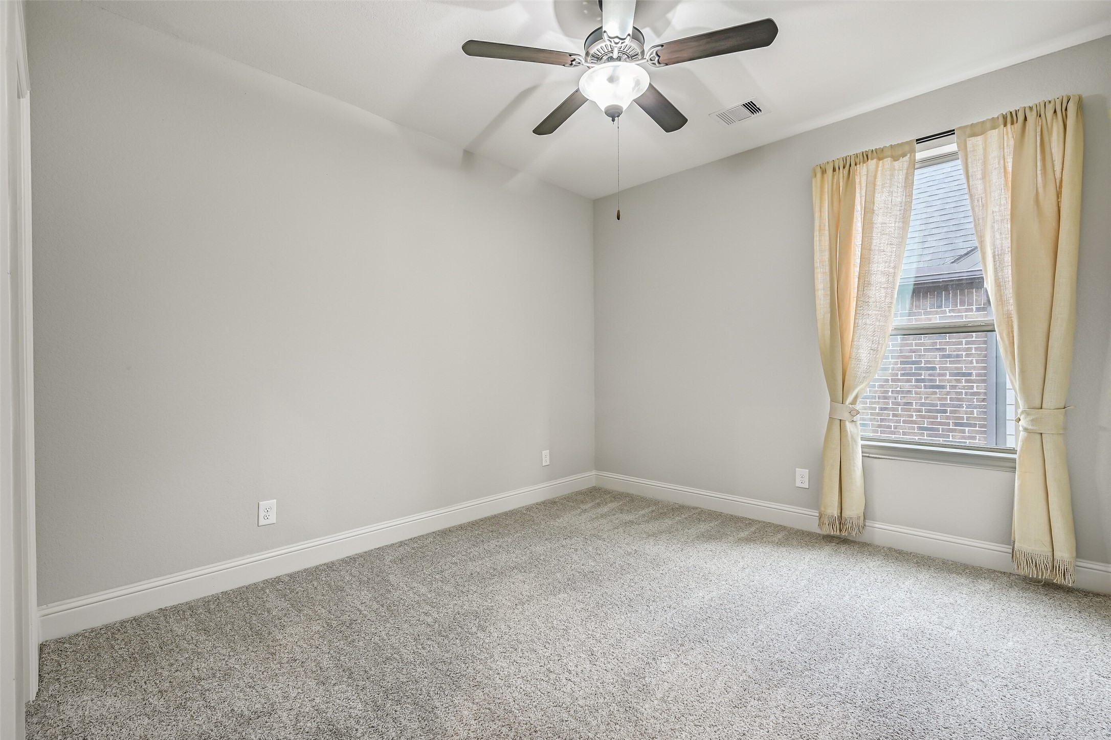 Just off the game room, this comfortable secondary bedroom features plush carpeting, neutral walls, a lighted ceiling fan & side-facing window with draperies. A walk-in closet provides additional storage, with convenient access to the nearby full bathroom.
